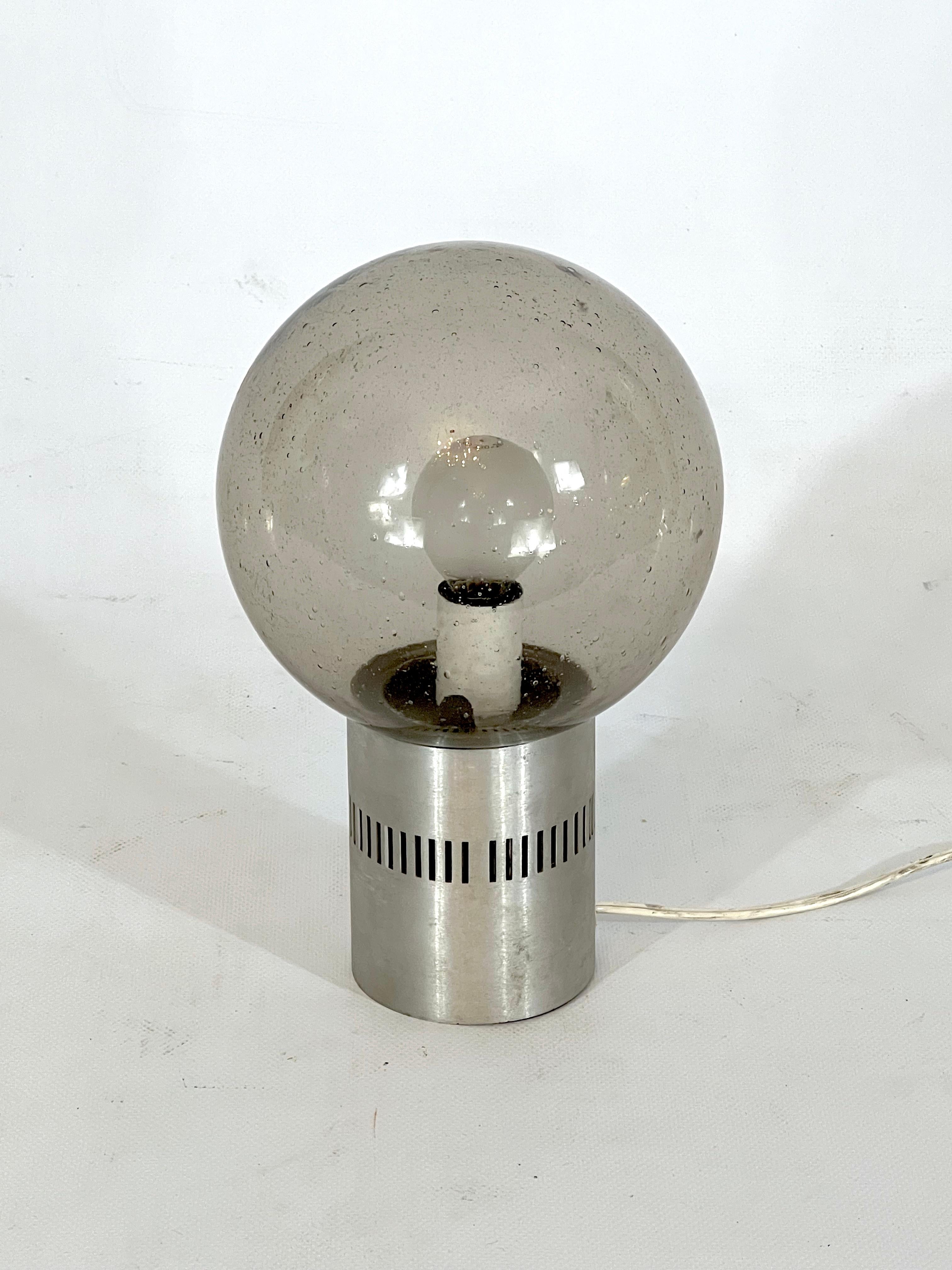 Bon état vintage pour cette lampe de table produite par Stilux Milano durant les années 60 et réalisée en aluminium brossé et verre bullicante. Fonctionne entièrement avec la norme européenne, adaptable sur demande à la norme américaine.