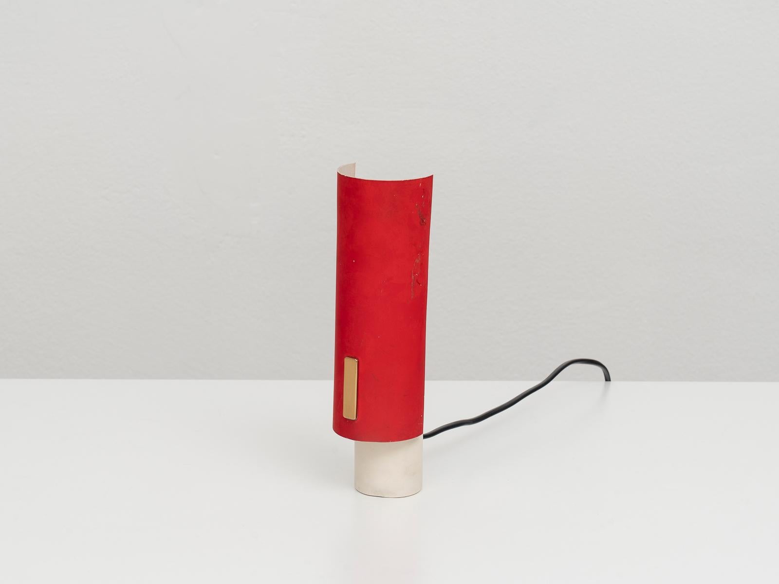 This Mid-Century Modern table lamp was manufactured by Stilux Milano in the 1960s. It is made of cream and red varnished metal with brass details. It mounts one E16 light bulb.