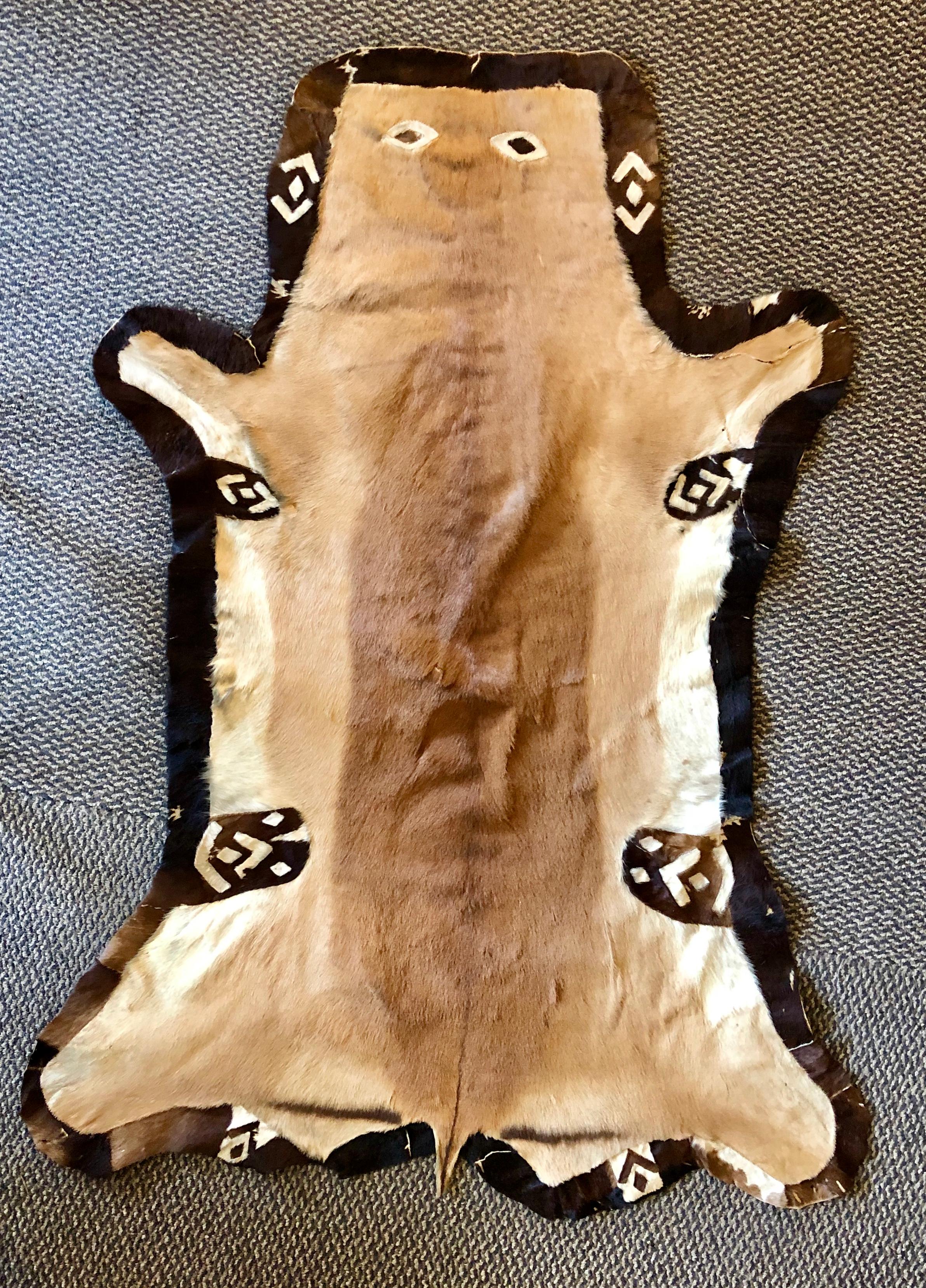 Stitch animal skin rug or carpet with a happy face. This hand stitched animal skin doesn't seem to mind being captured and placed on a floor or hung on the wall as she is seemingly smiling. Much different than the norm as this piece has a lining and
