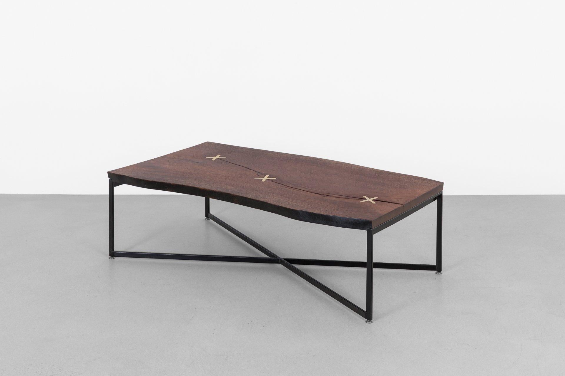 The Stitch coffee table showcases the rich grain of gorgeous walnut slab. Each coffee table embraces walnut's naturally occurring checks, which are reinforced with X-shaped brass stitches. The inset stitches beautifully contrast the chocolate tones