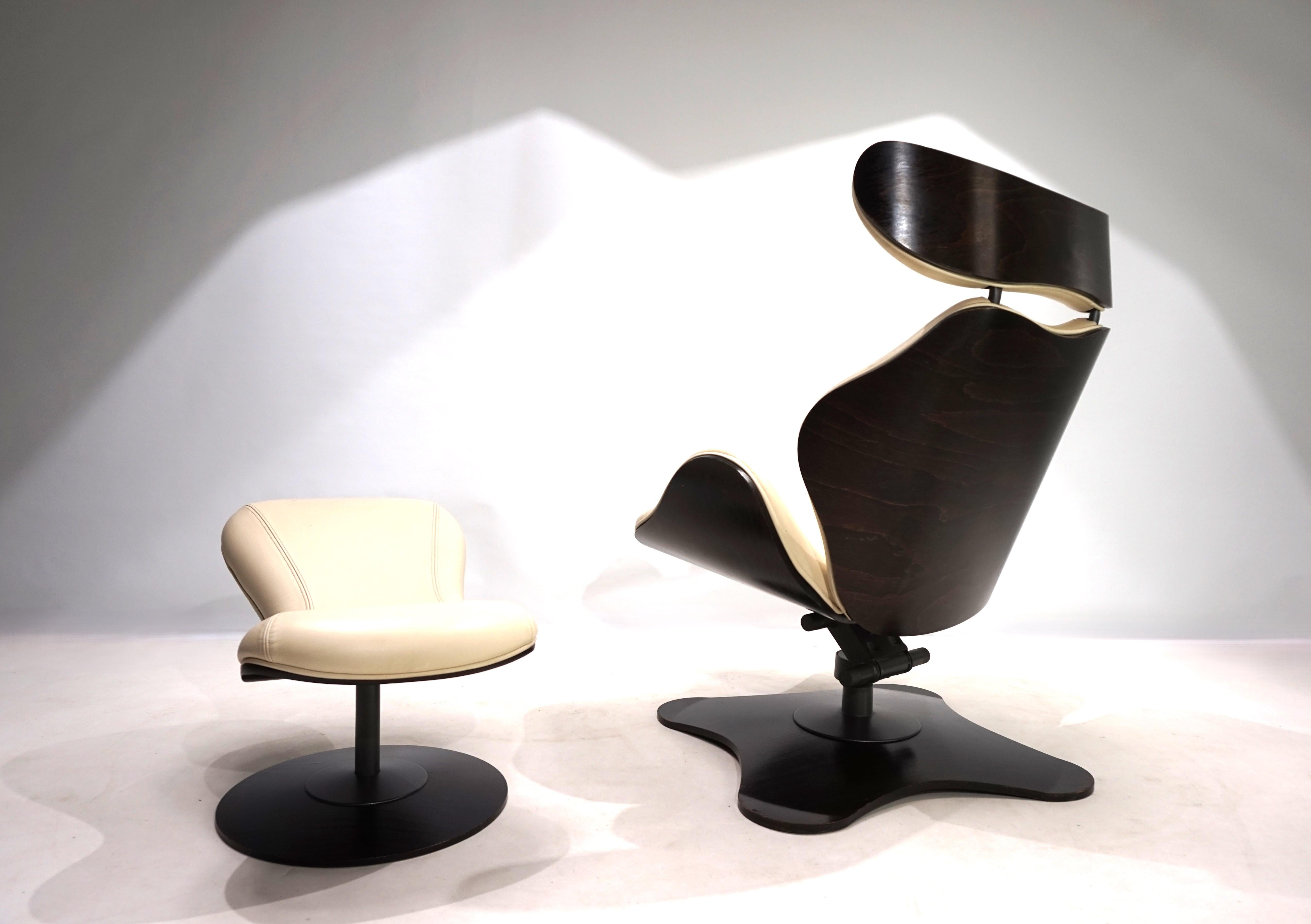 The Tok leather armchair with ottoman comes in ivory leather and a dark brown back and seat made of walnut with a very attractive grain. The leather shows slight signs of wear on the corners of the armchair and ottoman. The wooden shell is in very