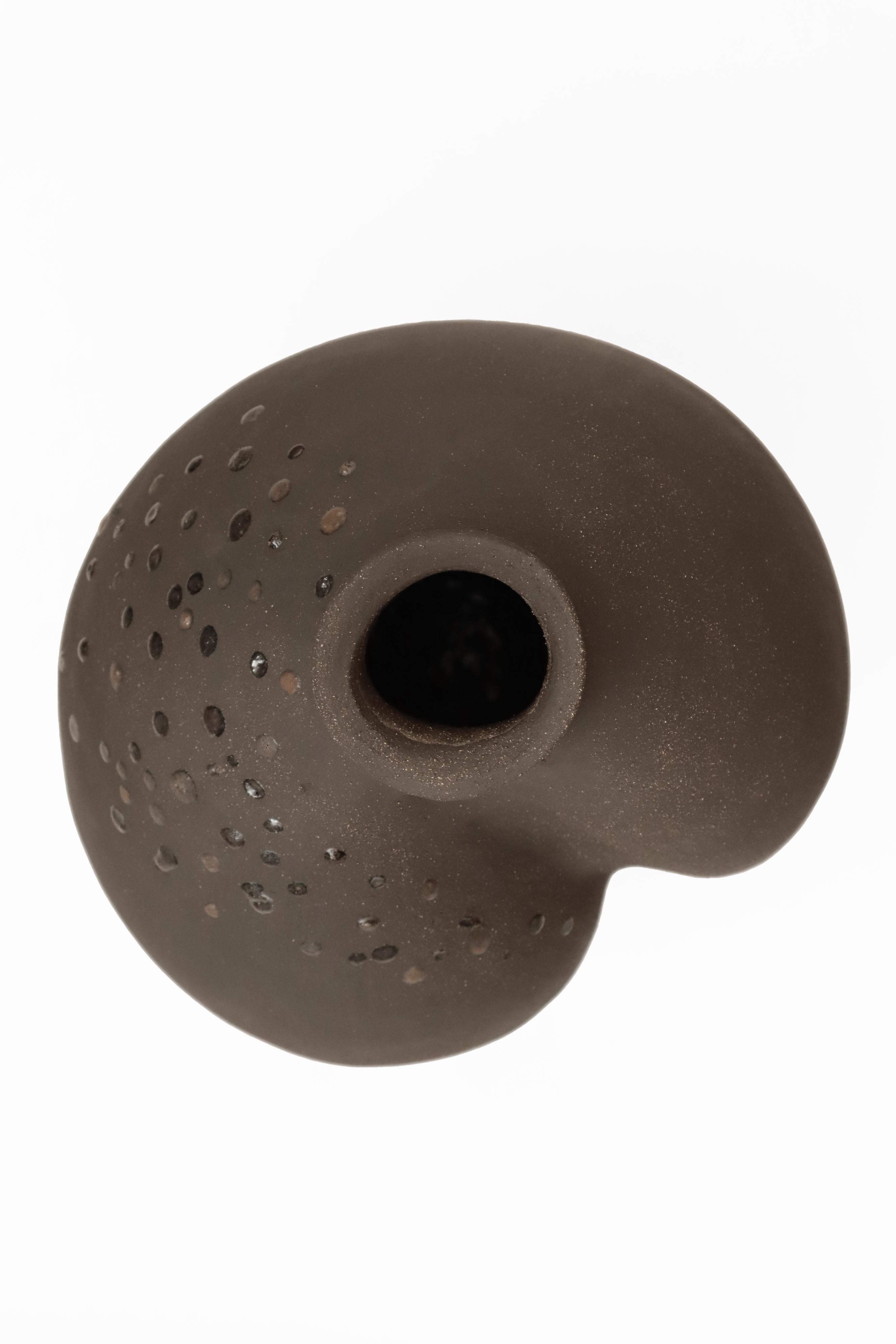 Stomata 12 vase by Anna Karountzou
Dimensions: W 25 x D 23 x H 36 cm
Materials: Black stoneware clay, clear glaze inside, decorated outside with volcano rocks collected from Santorini, fired at 1240

Born and based in Athens, Greece, with a
