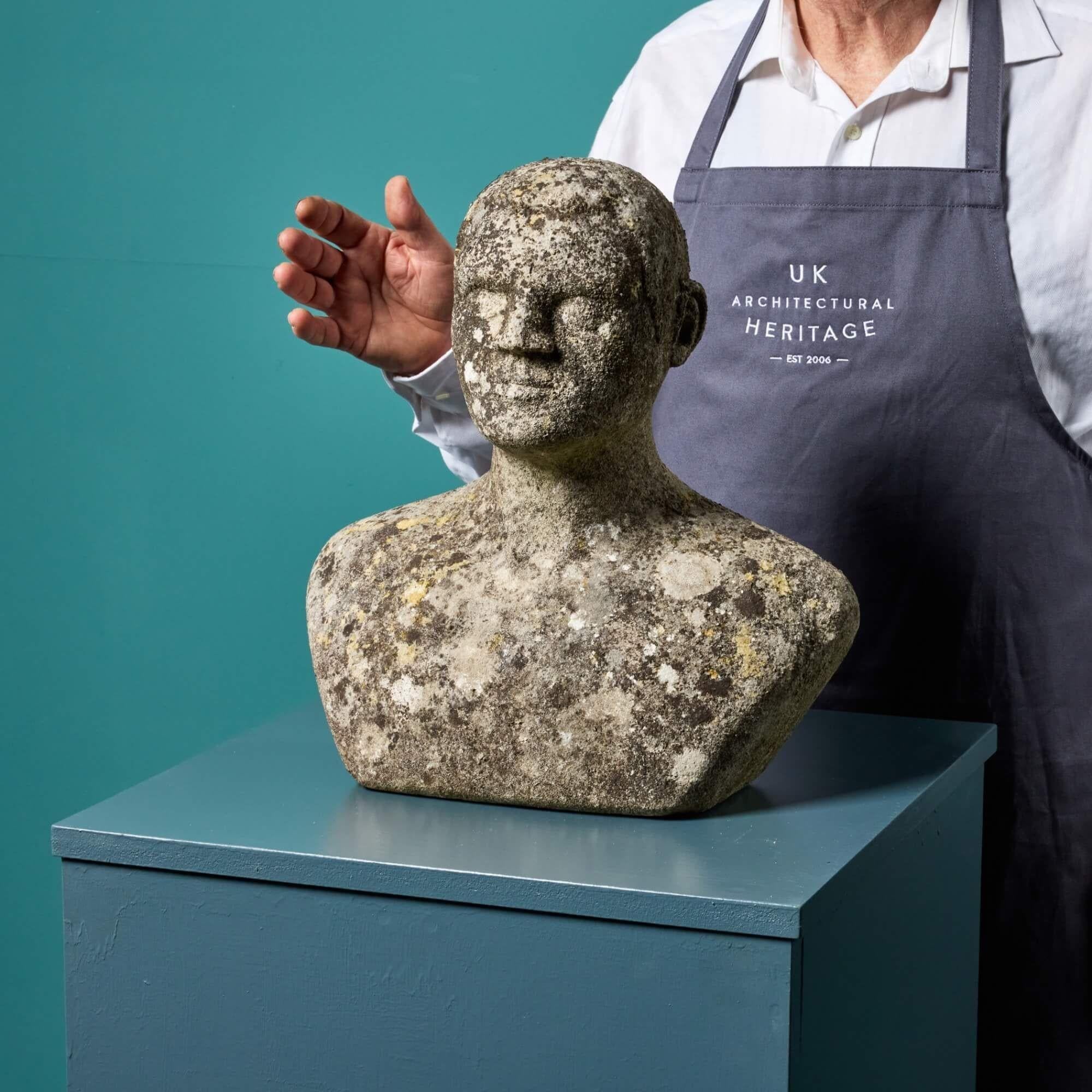 This carved stone head bust sculpture was reputedly carved by a student of 20th century British architect and artist, Sir Hugh Casson. It depicts the shoulders and head of a man in stone with a neutral expression and weathered surface finish that
