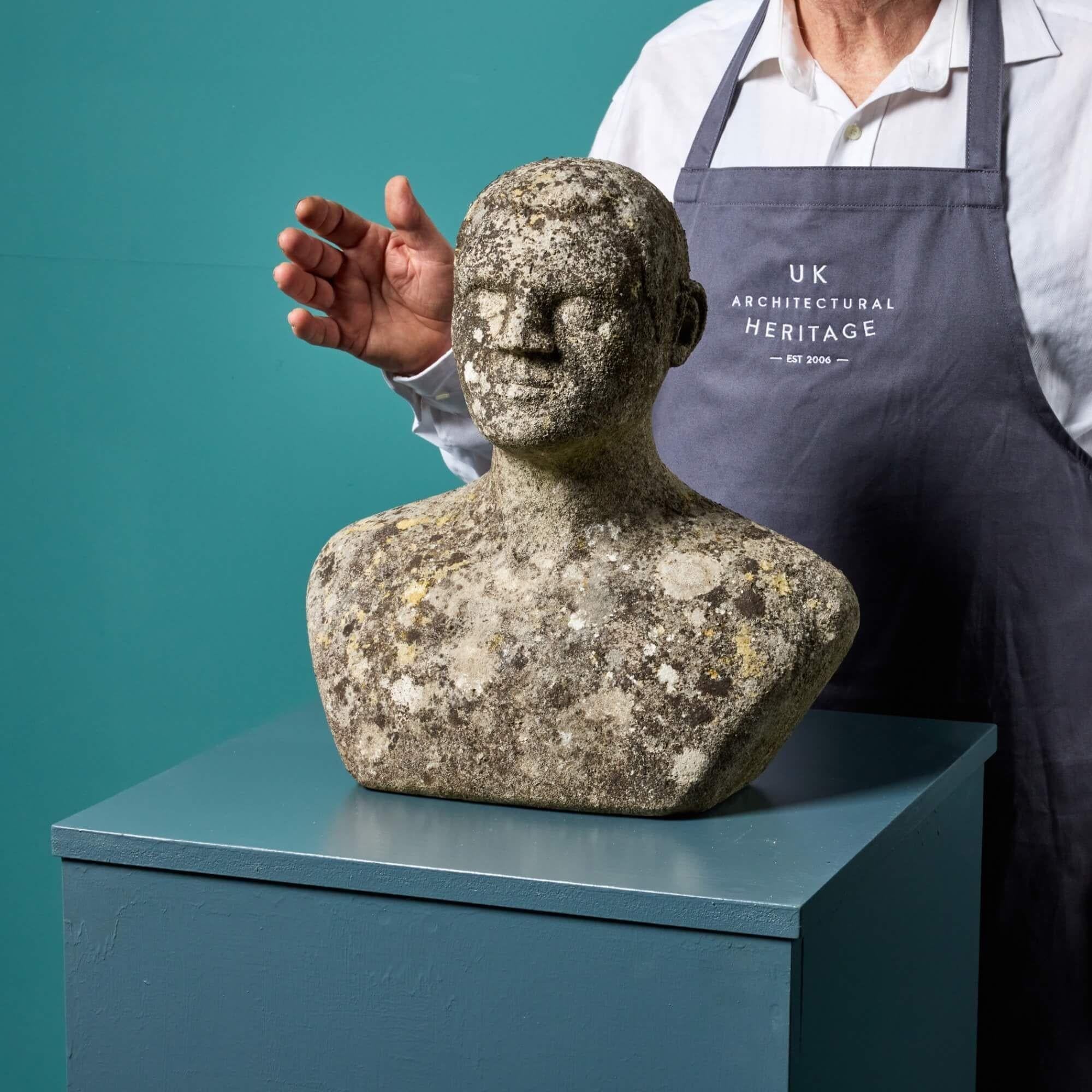 Questa scultura di testa in pietra scolpita è stata presumibilmente scolpita da uno studente dell'architetto e artista britannico del XX secolo, Sir Hugh Casson. Raffigura le spalle e la testa di un uomo in pietra, con un'espressione neutra e una