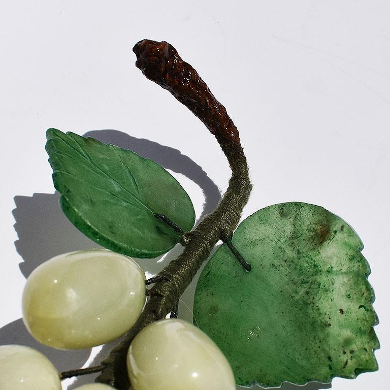 Cluster of carved stone grapes in a multitude of greens. A fabulous piece for accenting any table. This beauty features rounded oval carved grapes in green stone in a jade like hue. The cluster is tied together in green thread covered wire and