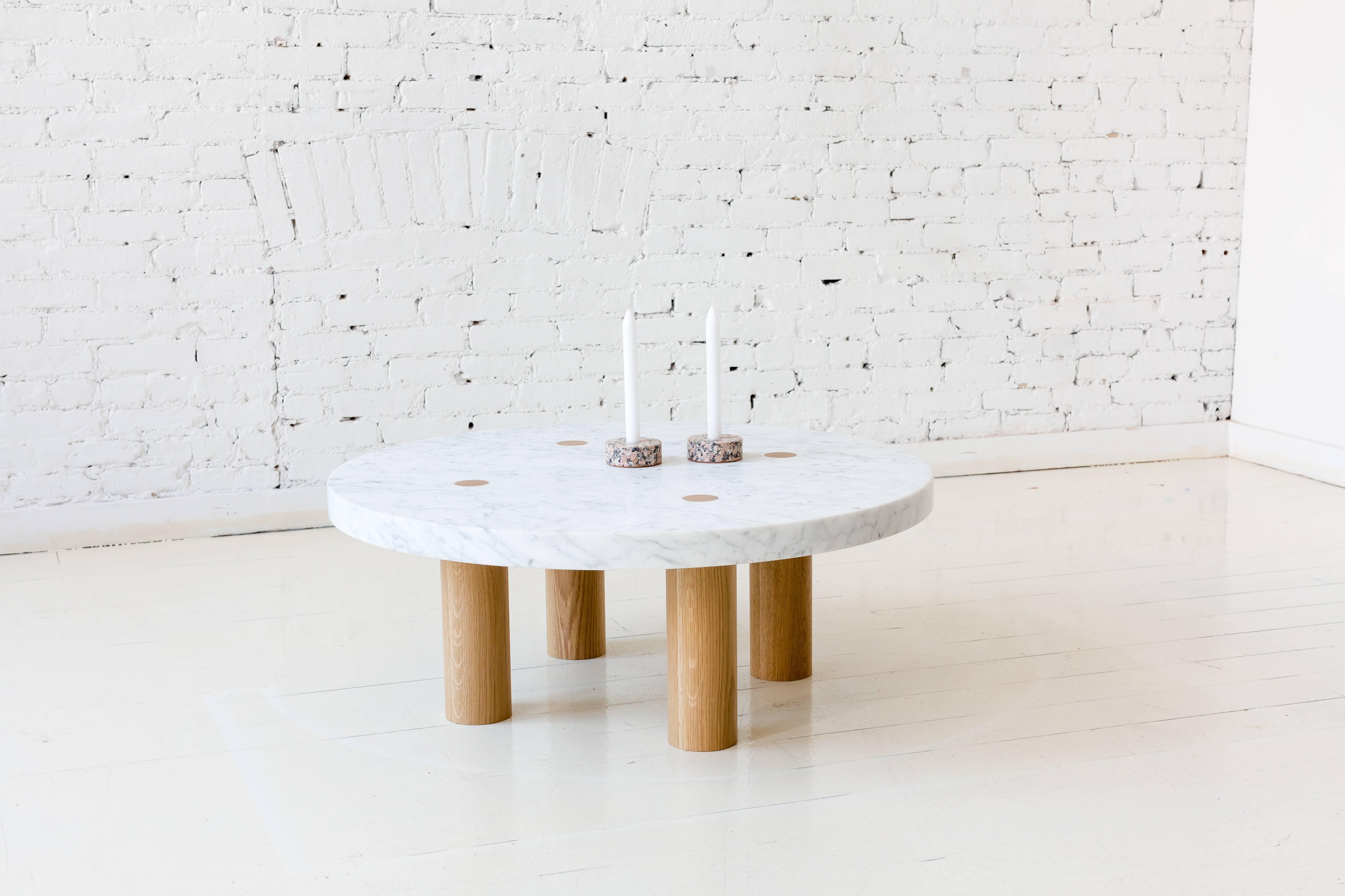 This contemporary, minimal coffee table features a marble top and hardwood legs. Each large round leg pierces the stone top to reveal the joinery and to remove the need for any other structural components. This detail communicates its solid