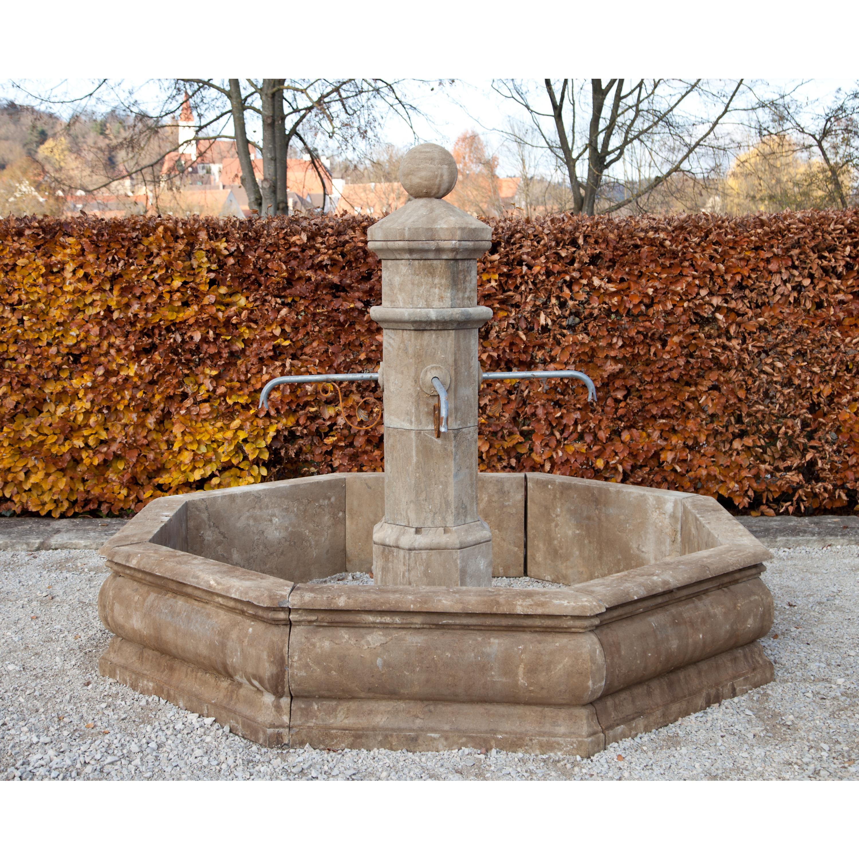 Courtyard fountain with octagonal basin with profiled walls. The fountain column with four spouts is also octagonal and crowned with a sphere. Made out of hand carved blue stone. (Measurement fountain border: 45 x 222 x 222 cm).