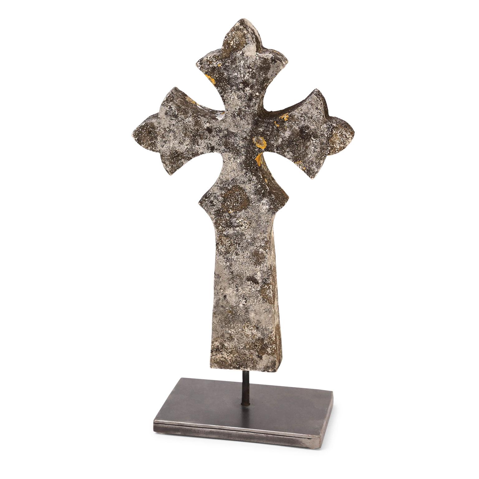 Stone cross mounted on steel stand.
  