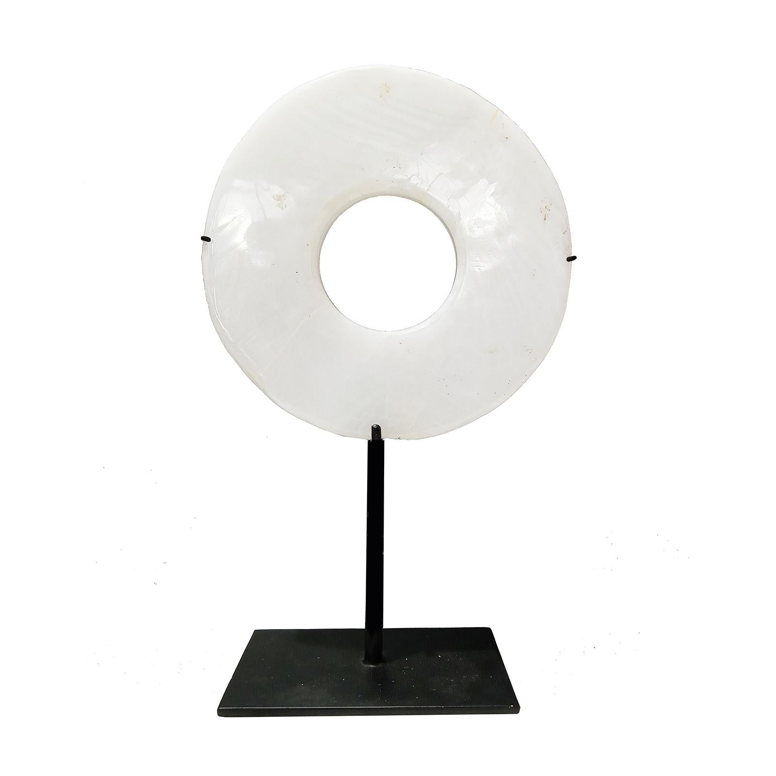 A beautiful stone disk, hand-carved in Indonesia. Mounted on a black metal stand. White stone, polished and shaped to resemble marble.

6.75 inches diameter, 2.75 inches deep (stand base), 11 inches total height (mounted). 


