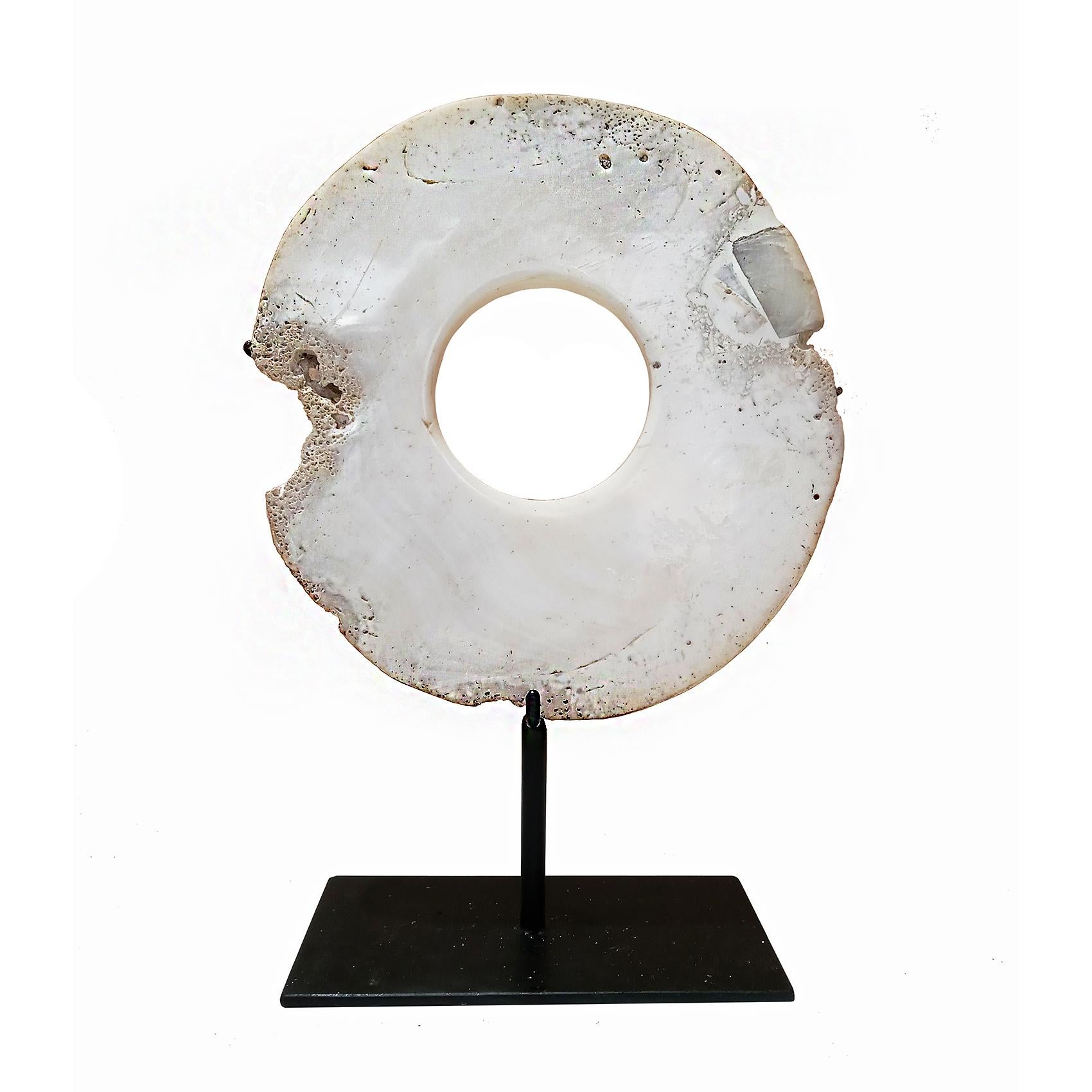 A beautiful stone disk, hand-carved in Indonesia. Mounted on a black metal stand. White stone, polished and shaped to resemble marble. 

7 inches diameter, 2.75 inches deep (stand base), 10 inches total height (mounted). 

Other stone disks from VW