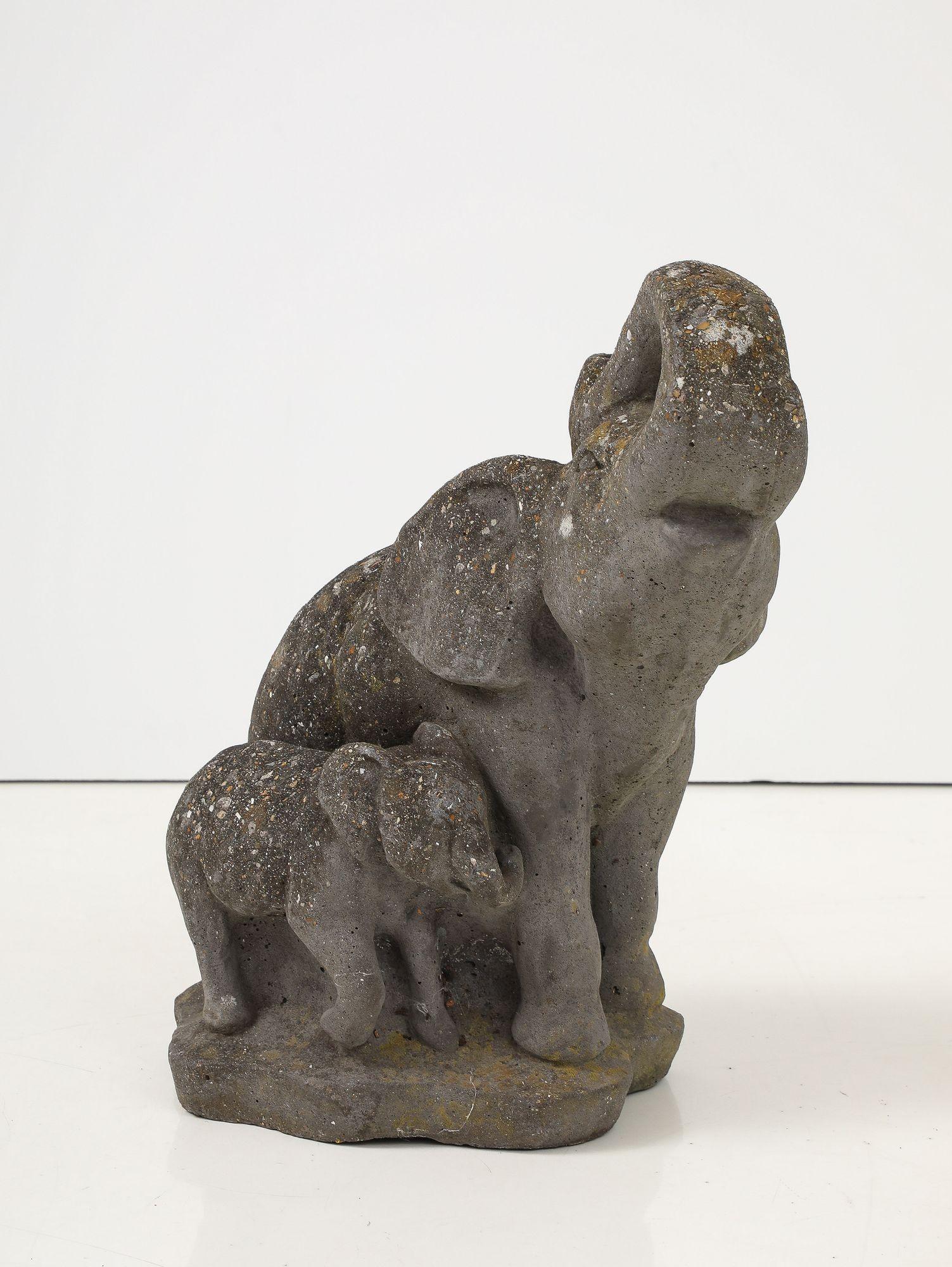 Cette charmante et ludique fontaine de jardin en pierre reconstituée, représentant une mère et son éléphanteau, provient de l'Angleterre du milieu du XXe siècle. La pièce capture magnifiquement l'essence d'une mère éléphant avec sa trompe levée,