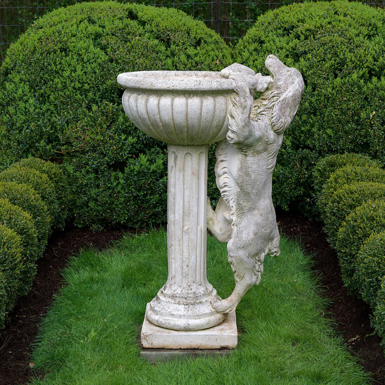 A composition stone fountain, the lobed bowl on fluted column and the whole being climbed by a curious spaniel, marked “DECORGARDEN”.