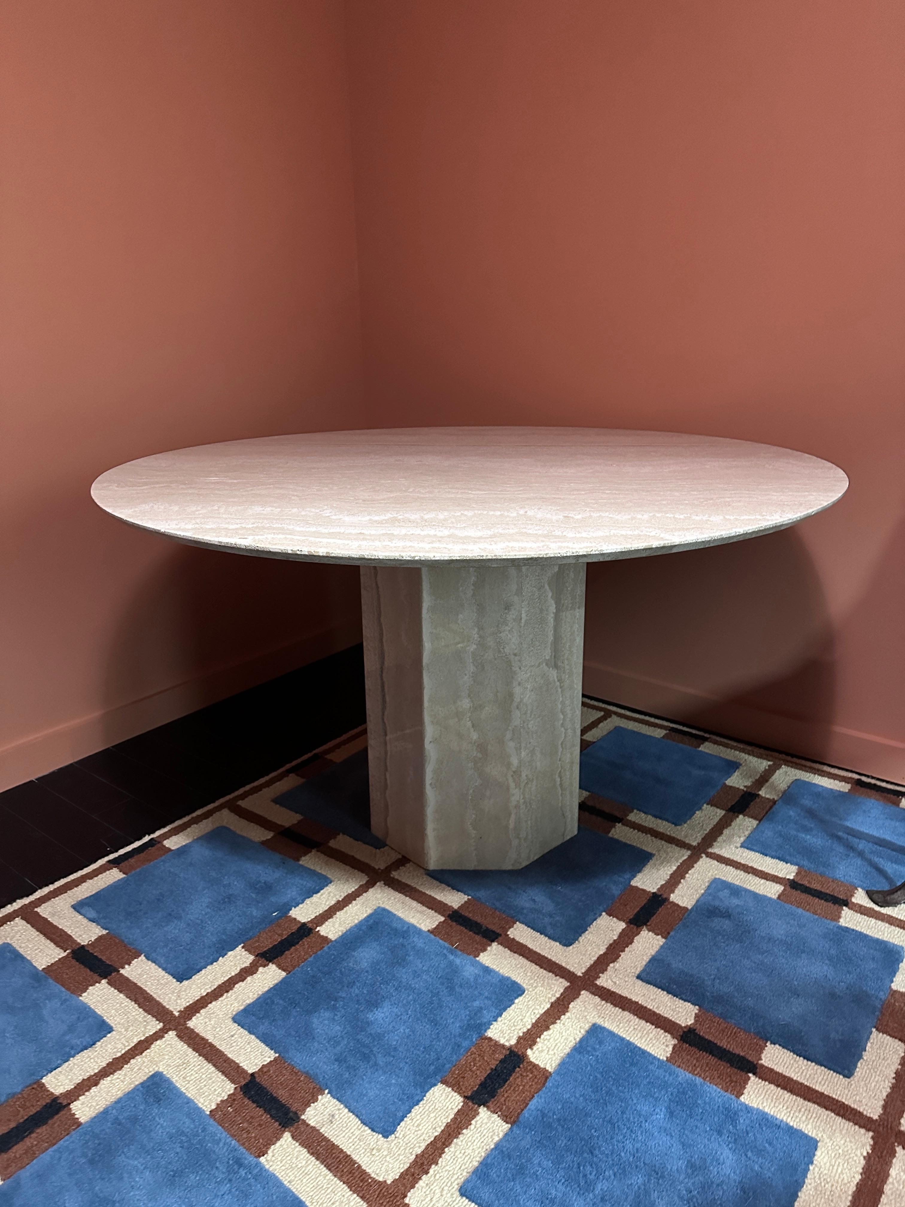 Round Italian travertine dining table with beautiful veining in creams, white, beige, and gray. Top enforced with thin wood. The top detaches from the base for easy transport. Base is octagonal. Minimal signs of age-related wear. Two minor non-sharp