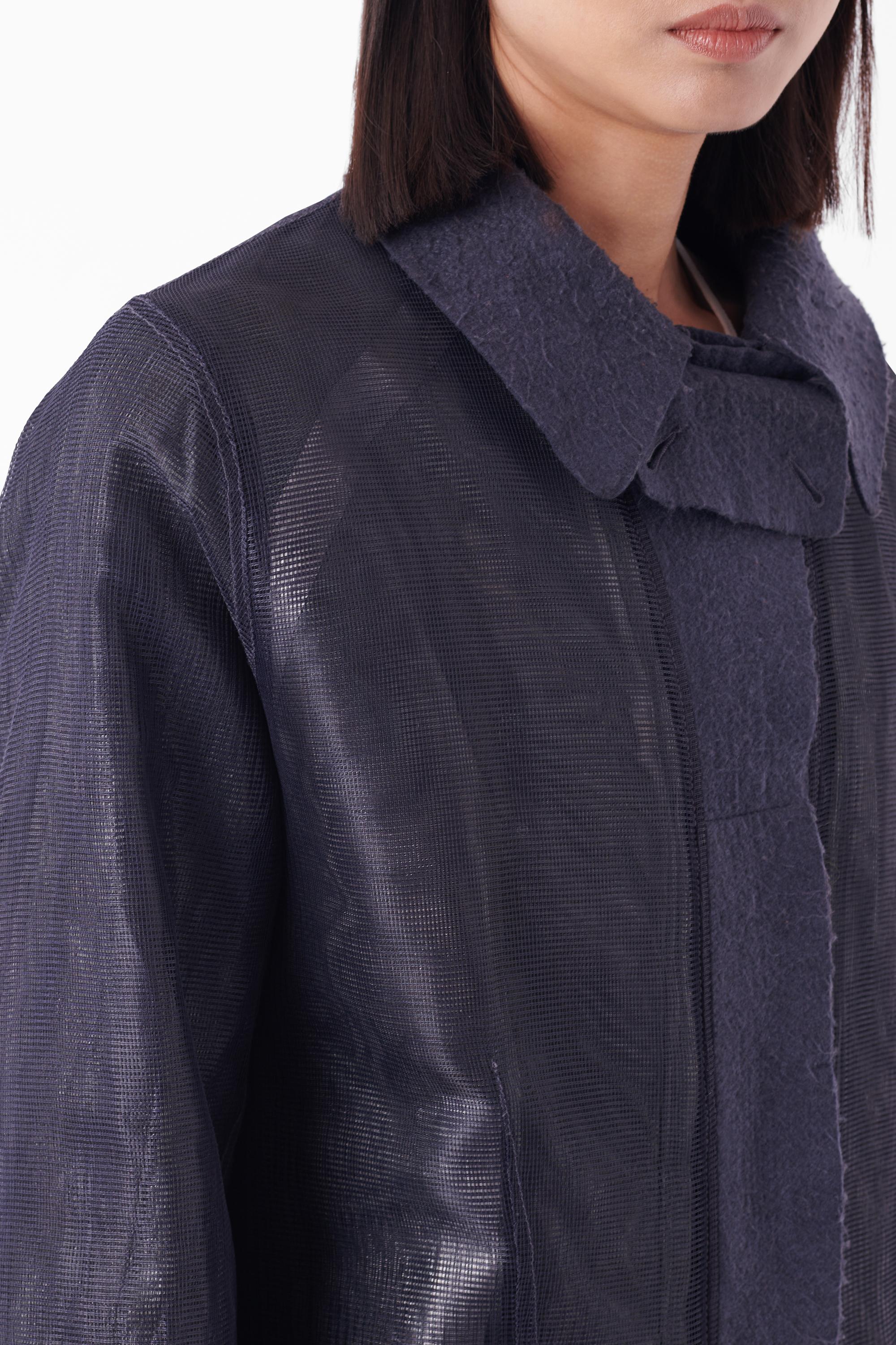 Cappotto a strati in rete blu Stone Island Serie 100 Autunno Inverno 2003. Tra il 2001 e il 2004 Stone Island ha prodotto sei stagioni della Serie 100 - Pezzi da collezione. Presenta un colletto in feltro con chiusura frontale a bottoni, un
