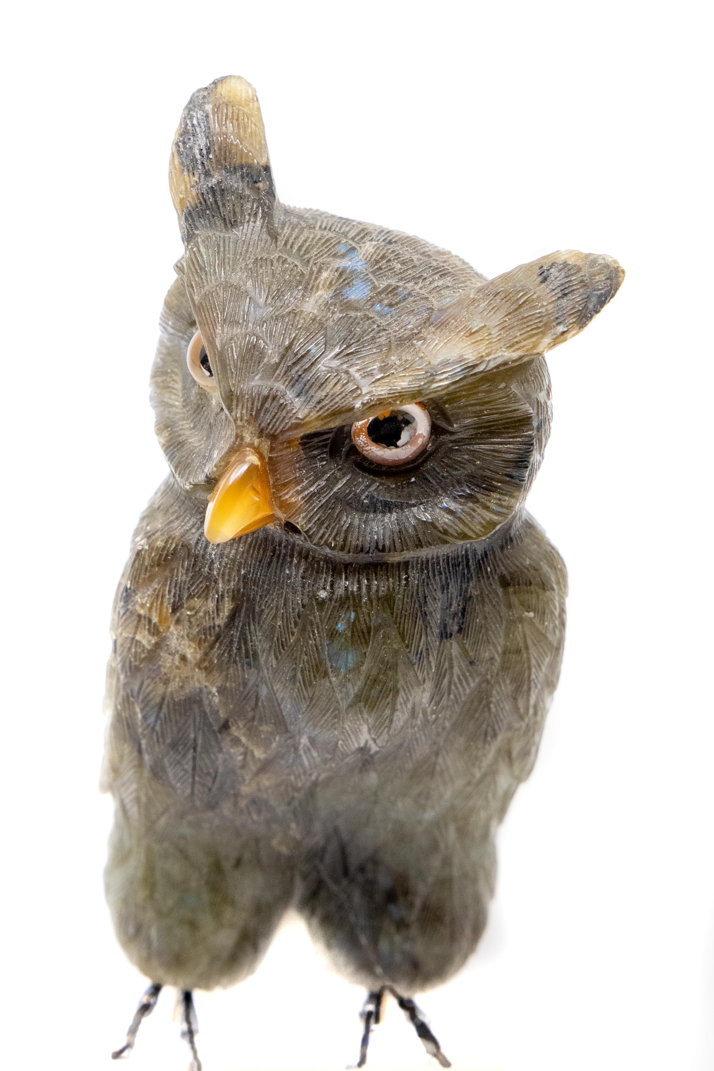 This gorgeous owl is carved of natural stone. Having intricate detail in the feathers. The stone has natural iridescent spots that turn different colors depending on lighting. Has spikes on the bottom so he could be attached to wood or set in stone.