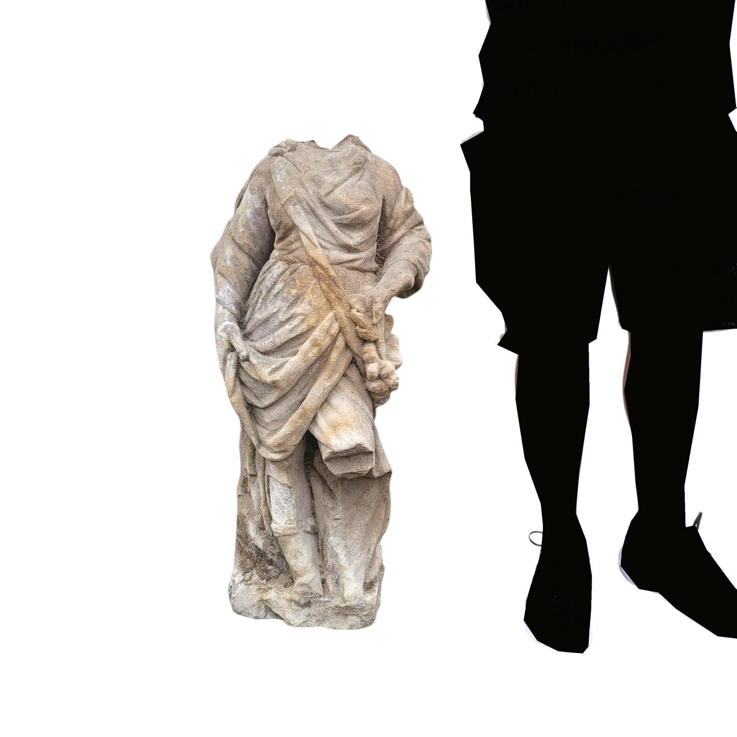Soft stone sculpture representing a standing person, headless, in a long draped garment.  

 Some losses and chips, wear.  

 Sculpture from the 16th or 17th century. 

  Height 88cm. 
 36 x 22cm.