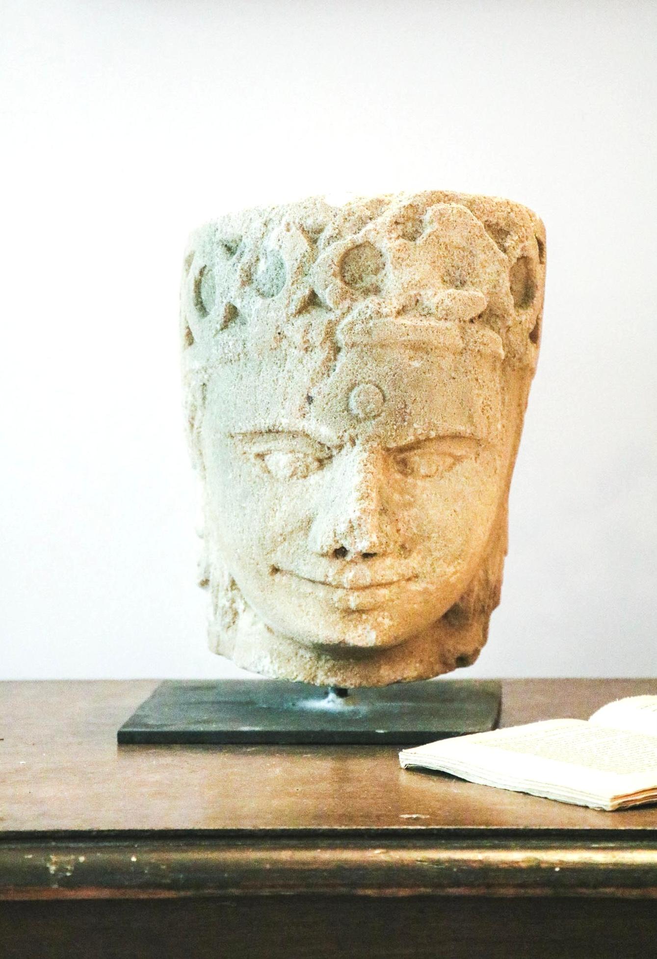 Beautiful stone sculpture featuring an Indian woman wearing earrings and a crown with rounds patterns carved. 
Mounted on a modern iron basement you could easily remove it.
Its simplicity and serenity of the face makes of it a beautiful piece of