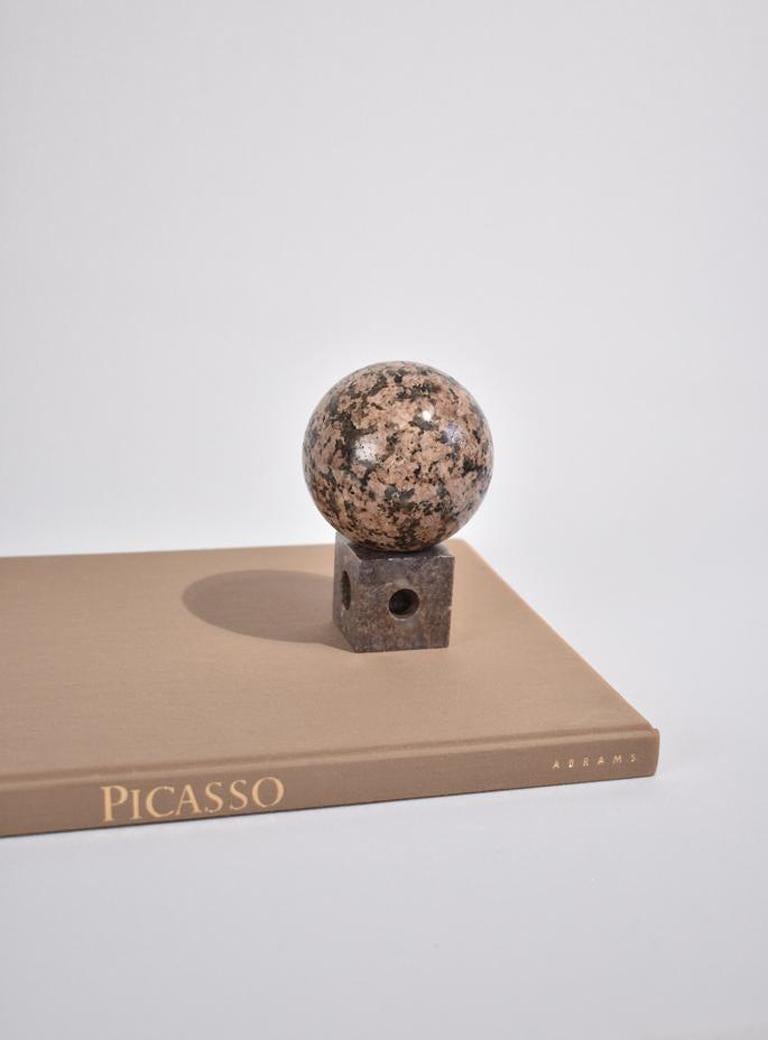 Vintage stone sphere sculpture in black, grey, and pink on a removable stone base. 
 