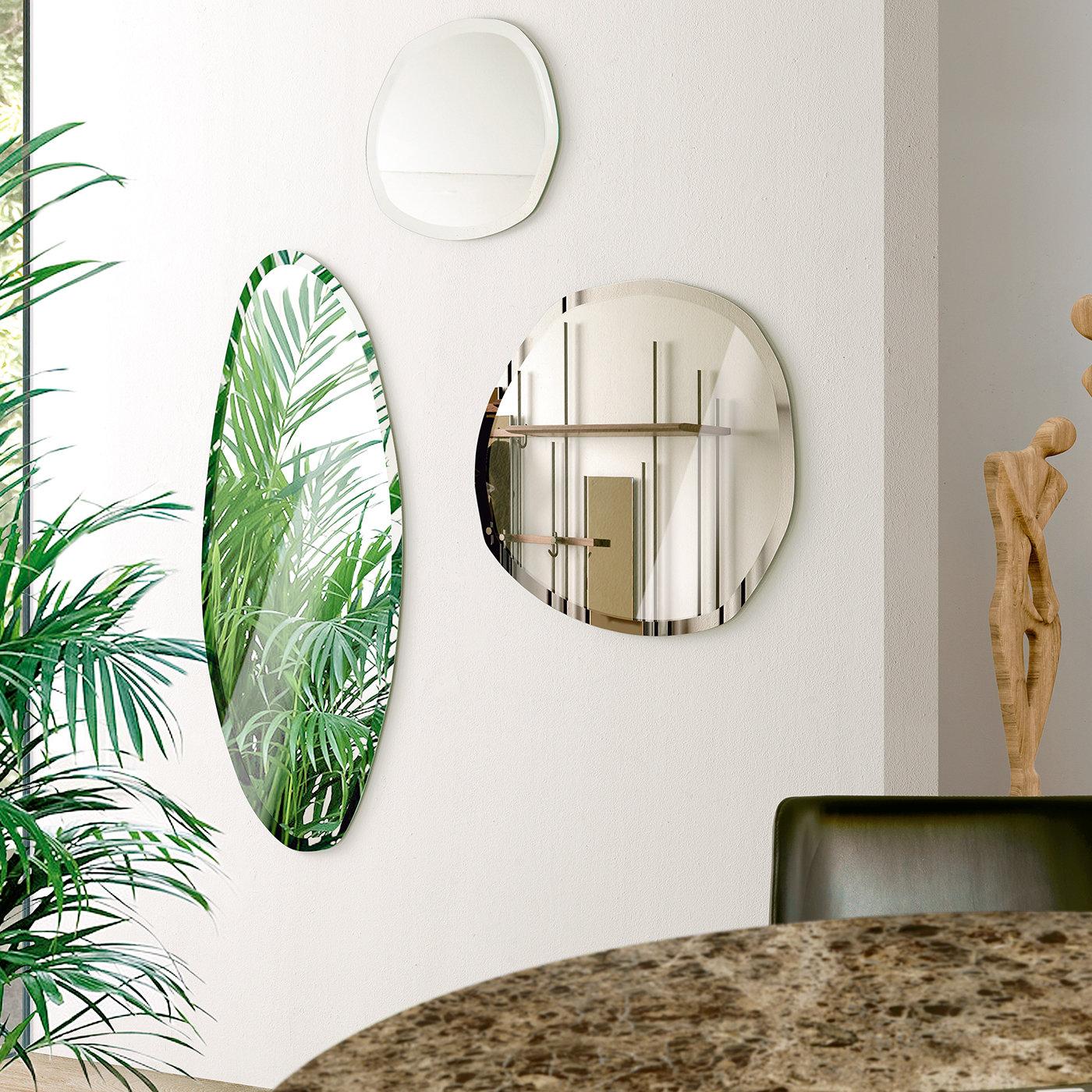 Defined by a slender and irregular shape, this stunning wall mirror by Norberto Delfinetti celebrates the organic charm of natural stone. The mirror is available in a natural or bronzed finish, and it is bordered by several beveled edges, designed