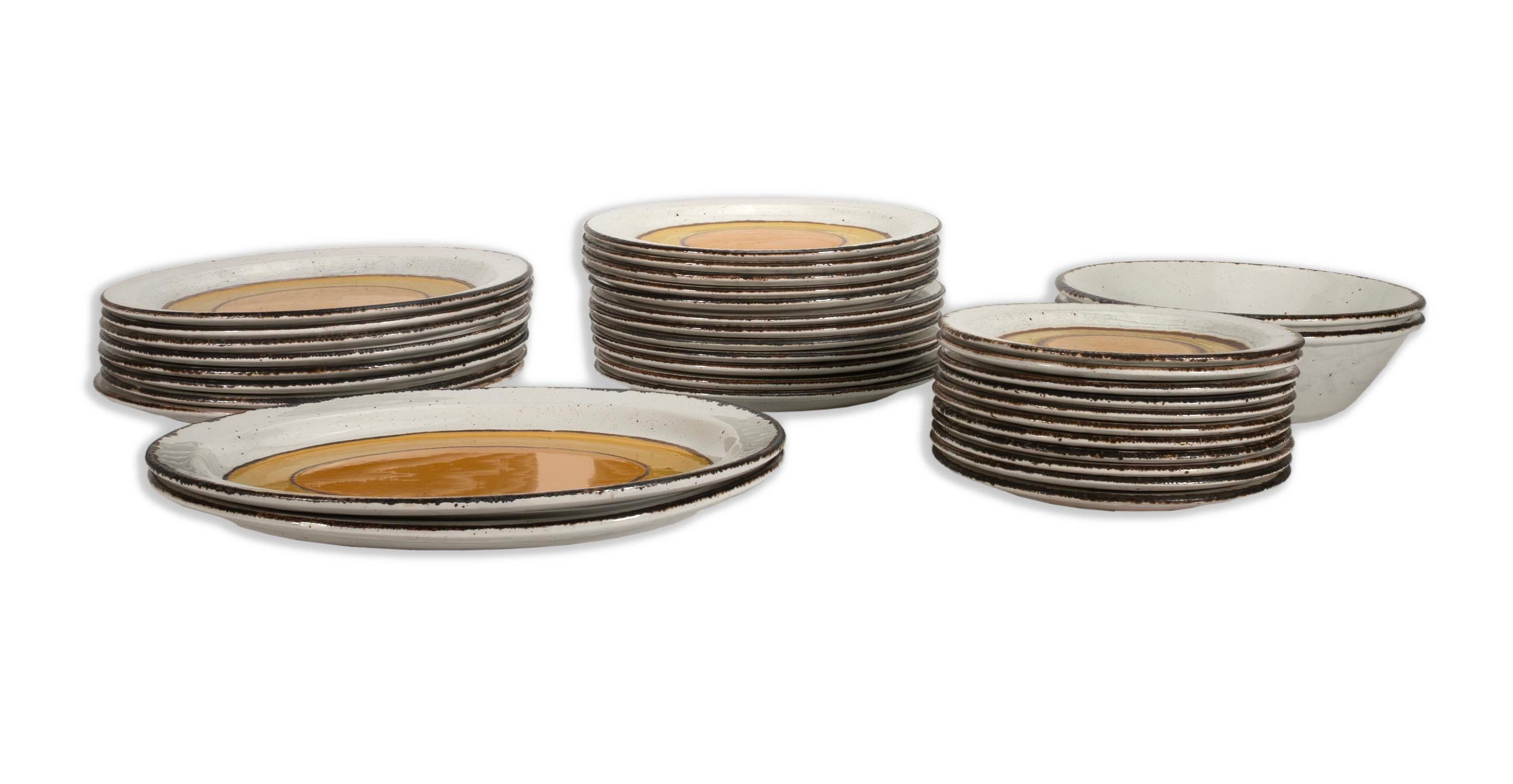 Elegant and timeless, this Stonehenge Mid Winter Sun Dinnerware Set of 33 exudes mid-century modern charm. Each piece features a captivating yellow and brown concentric circle design on a white background, showcasing the unique aesthetic of