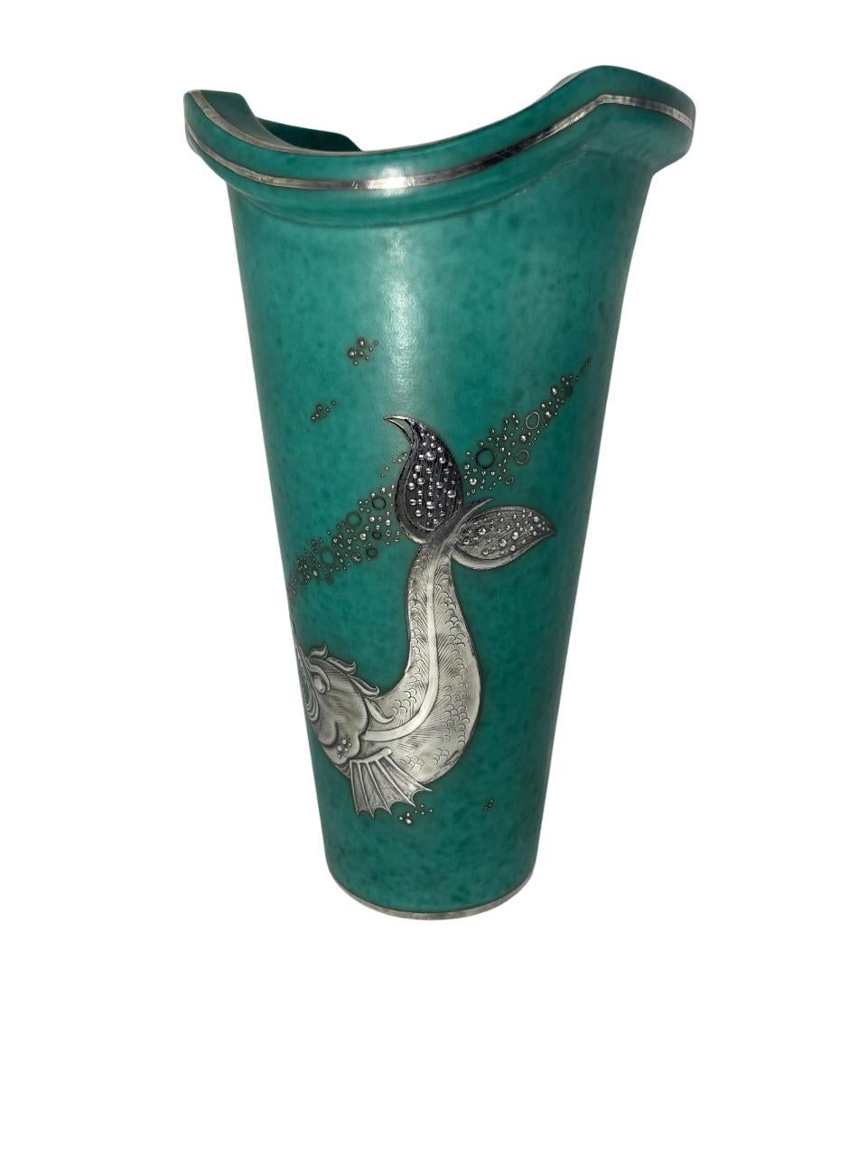 Elegante Art-Déco-Vase aus der berühmten Argenta-Serie, die Wilhelm Kåge in den 1930er Jahren für Gustavsberg in Schweden entwarf. Dieses Stück zeichnet sich durch die charakteristische grüne Craquelé-Glasur aus, die mit einem silbernen Überzug