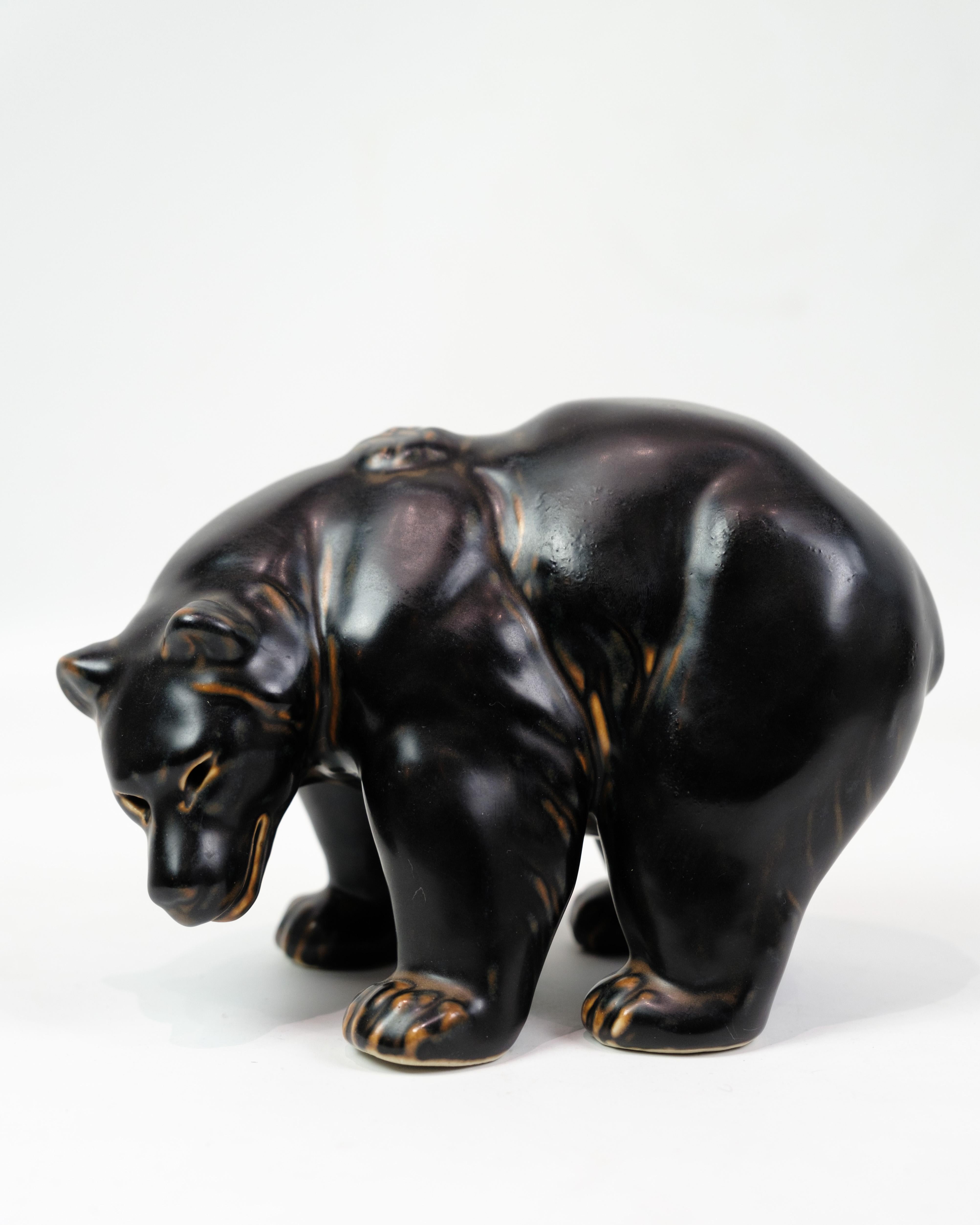 Cette magnifique figurine en grès, modèle 21519/237, représente un ours debout conçu par Knud Kyhn pour Royal Copenhagen. La figurine est en première année et mesure environ 15 cm de hauteur, 12,5 cm de largeur et 22 cm de profondeur.

Knud Kyhn