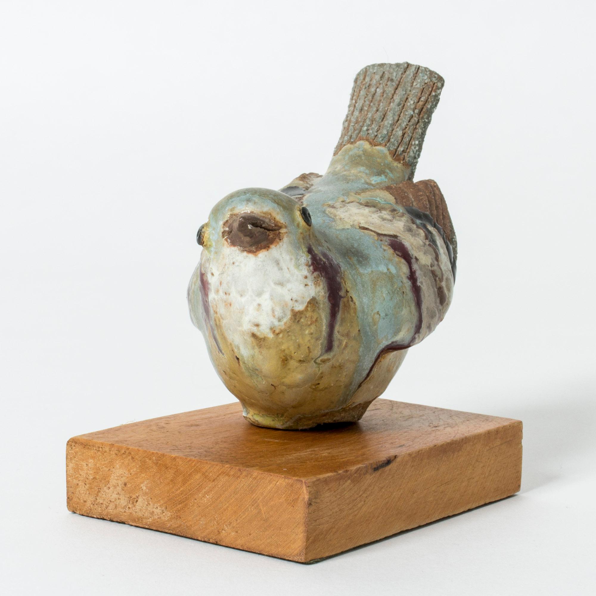 Lovely stoneware figurine by Tyra Lundgren in the form of a small bird. Intense and sensitive expression. Unglazed areas contrast with the thick, nature colored glazes that have flowed into the pattern of the feathers.