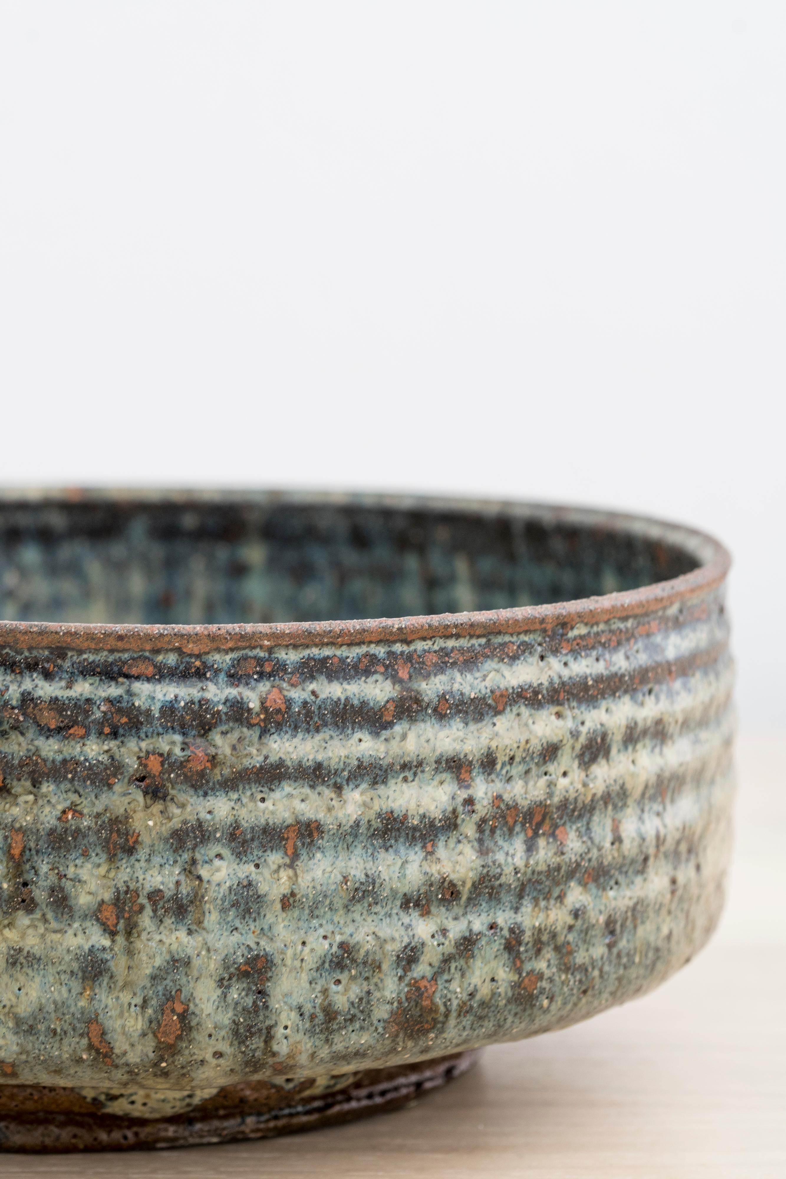 Stoneware bowl with impressed patterns and spiral to the well

Finished with grey and blue glazes, red and brown undertones

Incised with 
