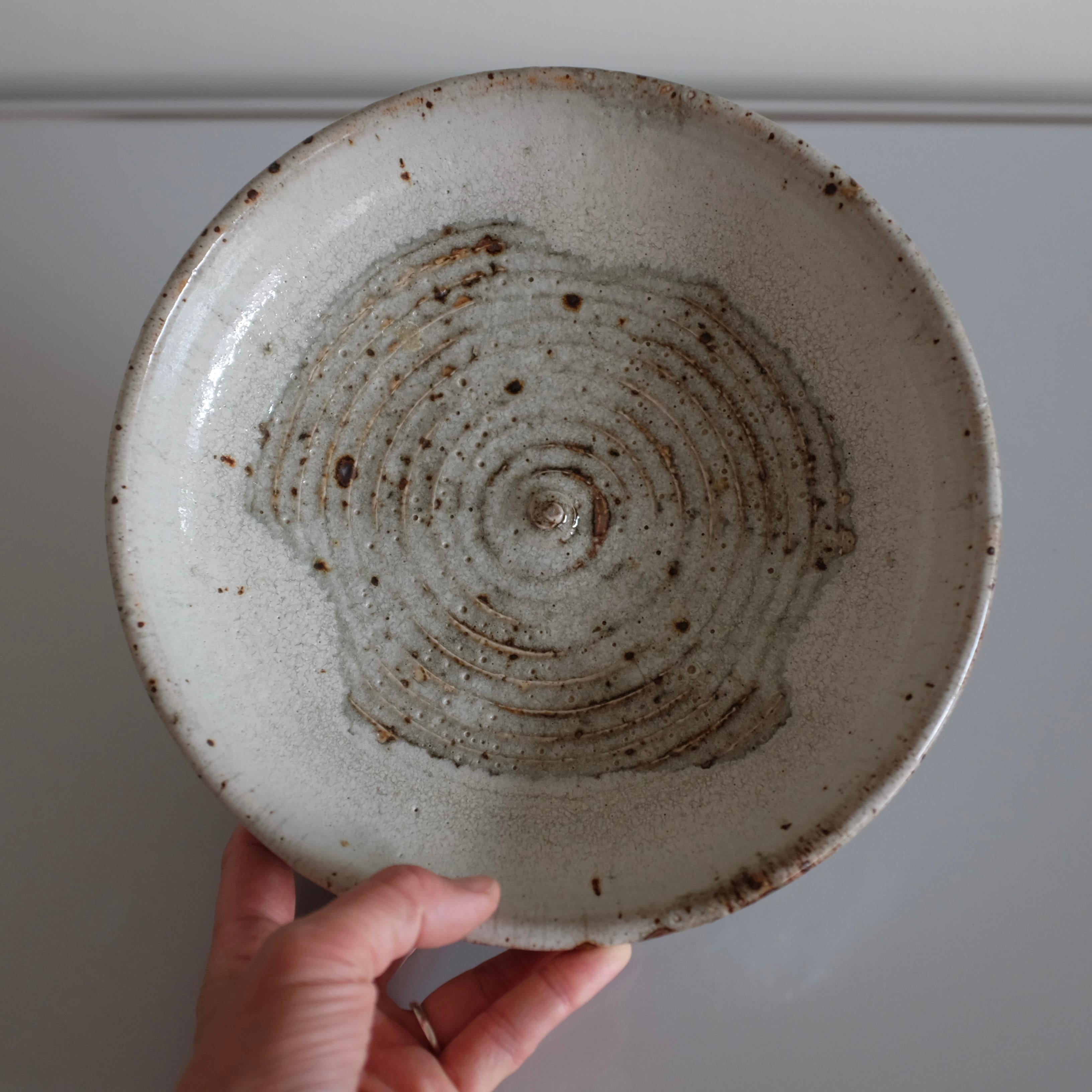 Coupe en grès moulée à la main dans les années 1960 par Marianne Westman Ateljé pour Rörstrand. La surface extérieure en blanc recouvre partiellement une forme intérieure en spirale avec des marques rustiques et brûlées, qui font toutes partie du