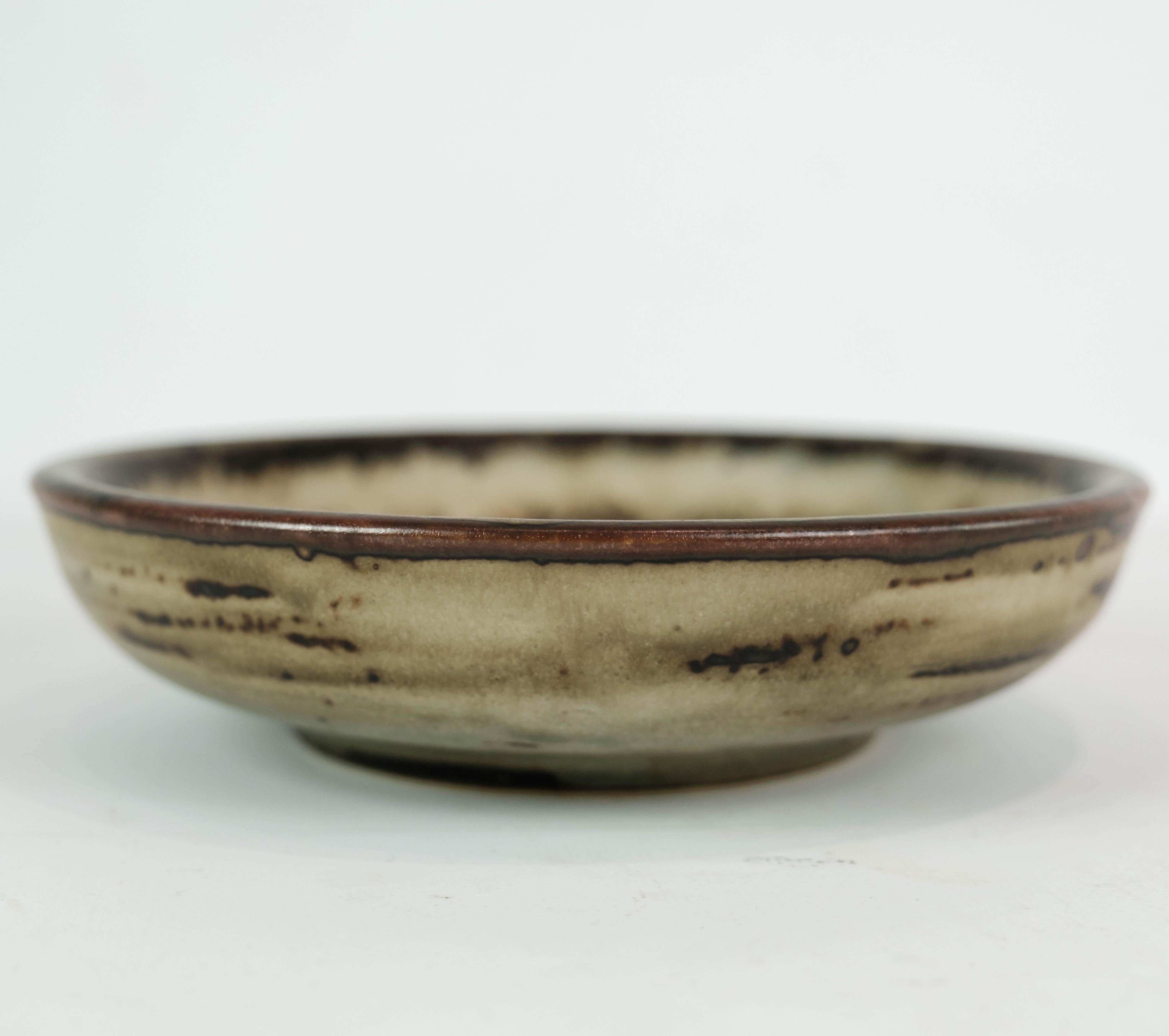This stoneware bowl, numbered 21567, is a stunning creation by the acclaimed Danish ceramic artist Gerd Bøgelund. Crafted with precision and finesse, it embodies the artistic excellence for which Bøgelund is renowned.

With its rich brown hues and