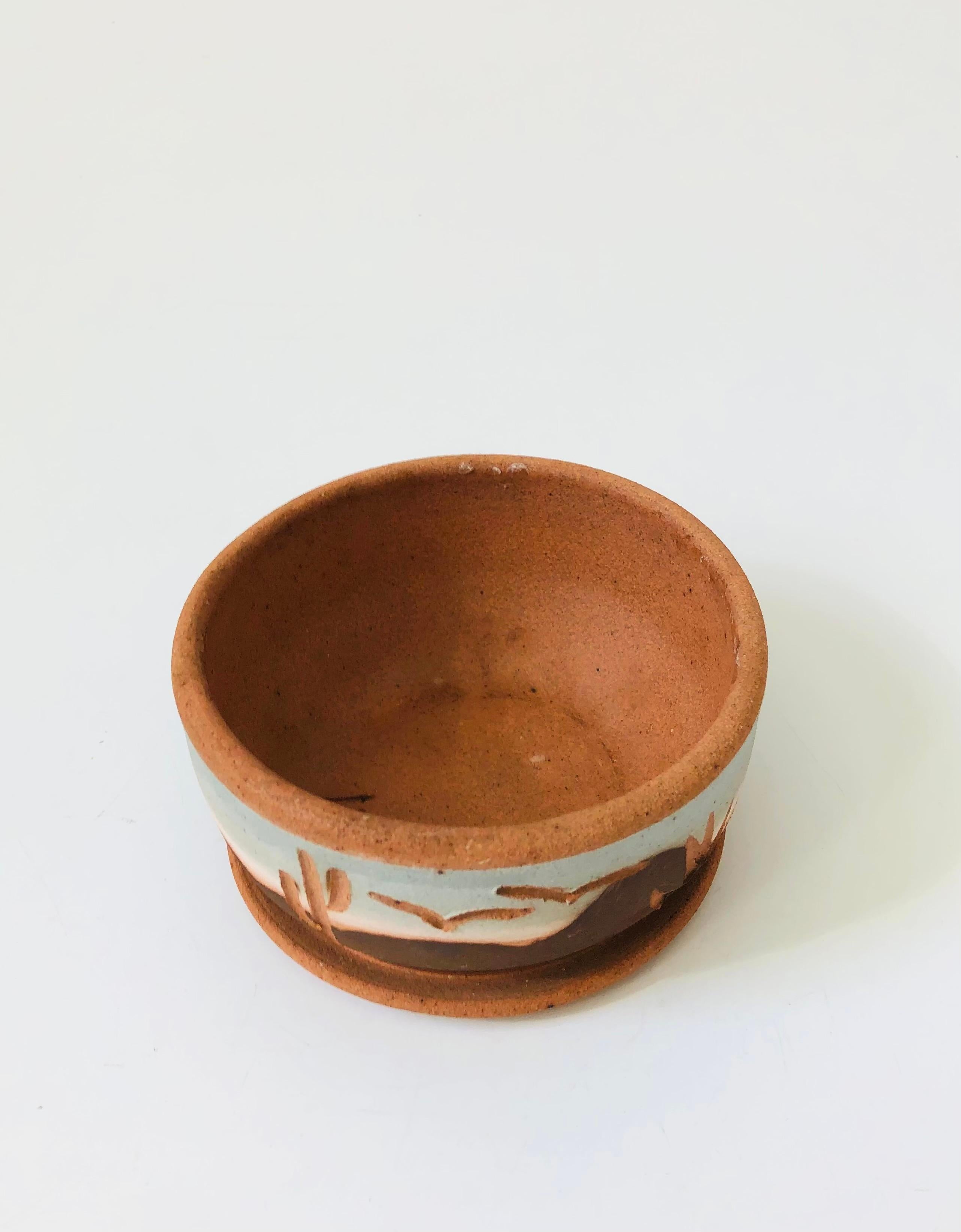 A vintage stoneware pottery shallow bowl planter. A beautiful southwestern landscape has been hand painted along the sides of the planter with cacti, agave, and birds carved into the sides exposing the terra cotta colored pottery for contrast. A