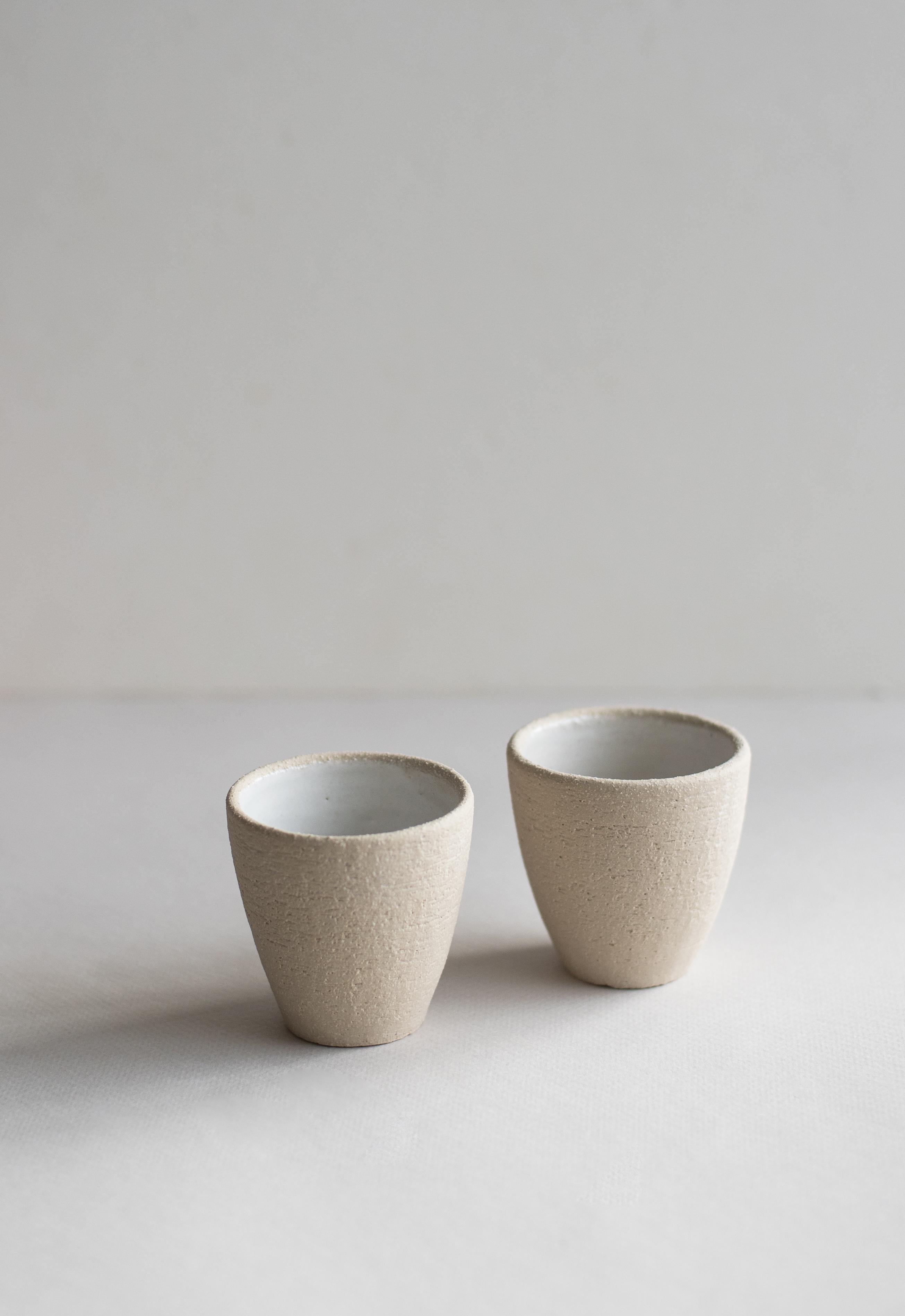 This tiny espresso cup with exposed clay from the outside and a white shiny glaze from the inside packs a petite punch as you caffeinate. Its shape and slightly rough texture bring fresh sophistication to the table.

- Stoneware
- Dishwasher-,