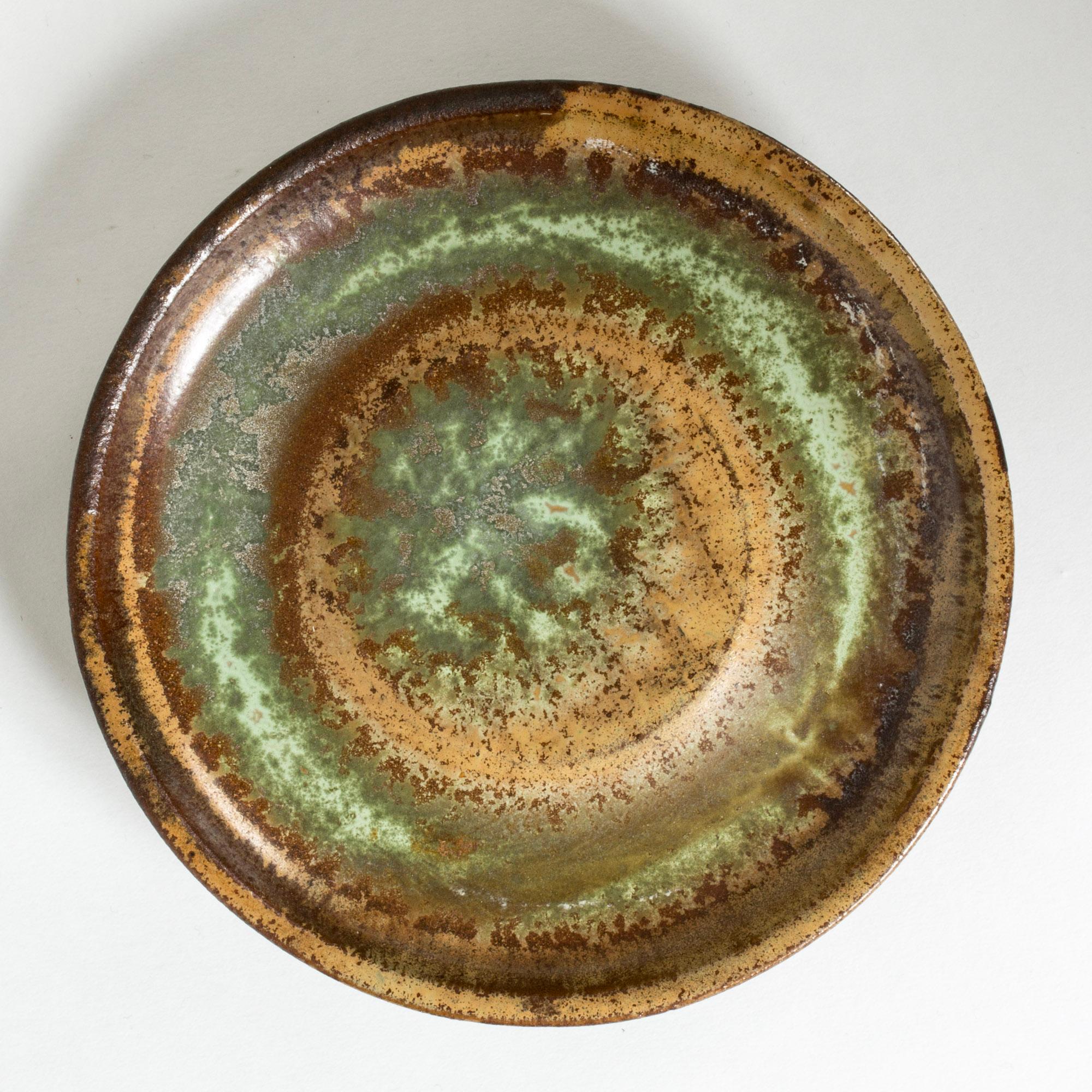 “Farsta” bowl or platter, made from stoneware in a smooth, thick form. Striking glaze in nuances of reddish brown, ochre and green.

“Farsta” stoneware is recognized as being the best and most exclusive that has come out of Swedish arts and crafts.