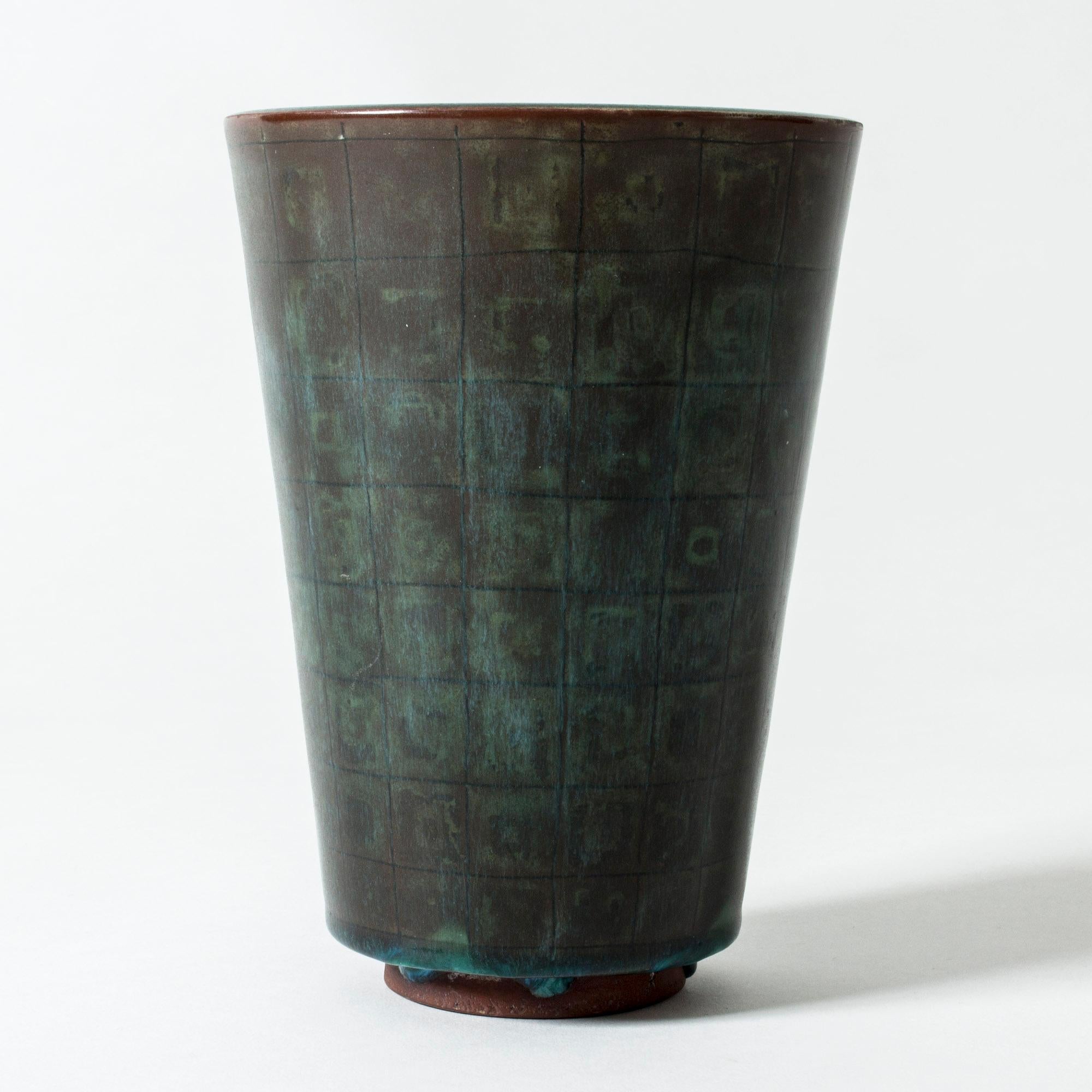 Simple yet striking “Farsta” vase by Wilhelm Kåge with clean lines and a subtle checkered pattern in the dark, patinated copper colored glaze.
“Farsta” stoneware is recognized as being the best and most exclusive that has come out of Swedish arts