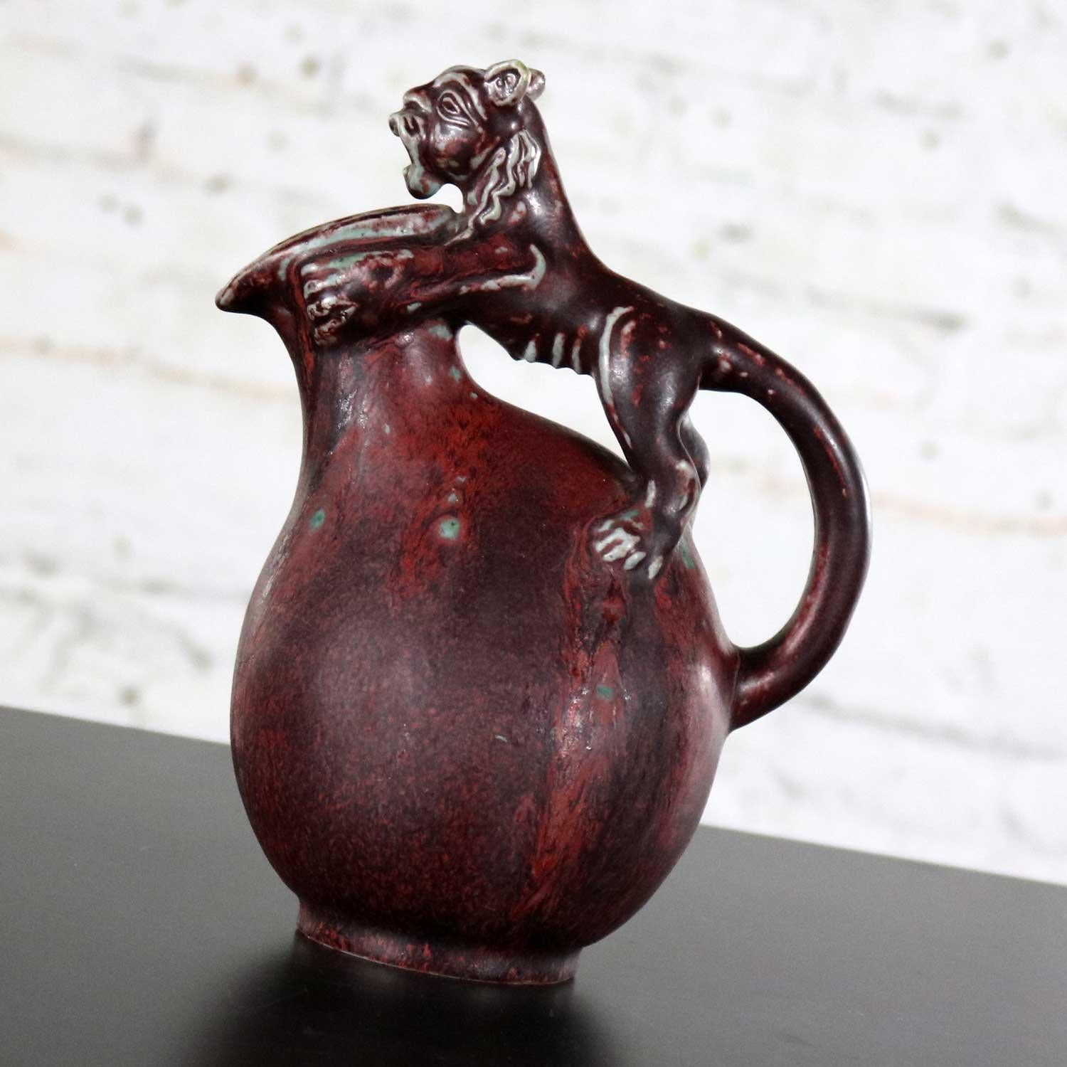 Handsome unique stoneware ceramic jug or ewer by Bode Willumsen for Royal Copenhagen. It is in an oxblood colored matt glaze and features a full body lion as the handle. Marked with Royal Copenhagen (crown) Denmark and the three rivers mark. You can