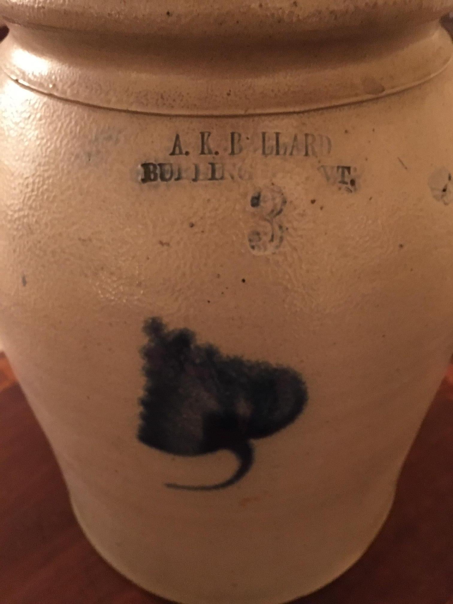 Stamped A.K. Ballard Burlington Vermont, this decorated stoneware jar is salt-glazed and features a 3 gallon capacity mark, a cylindrical form with slight shoulder, flat-top rounded galleried rim, beaded neck ring, applied arched ear handles,