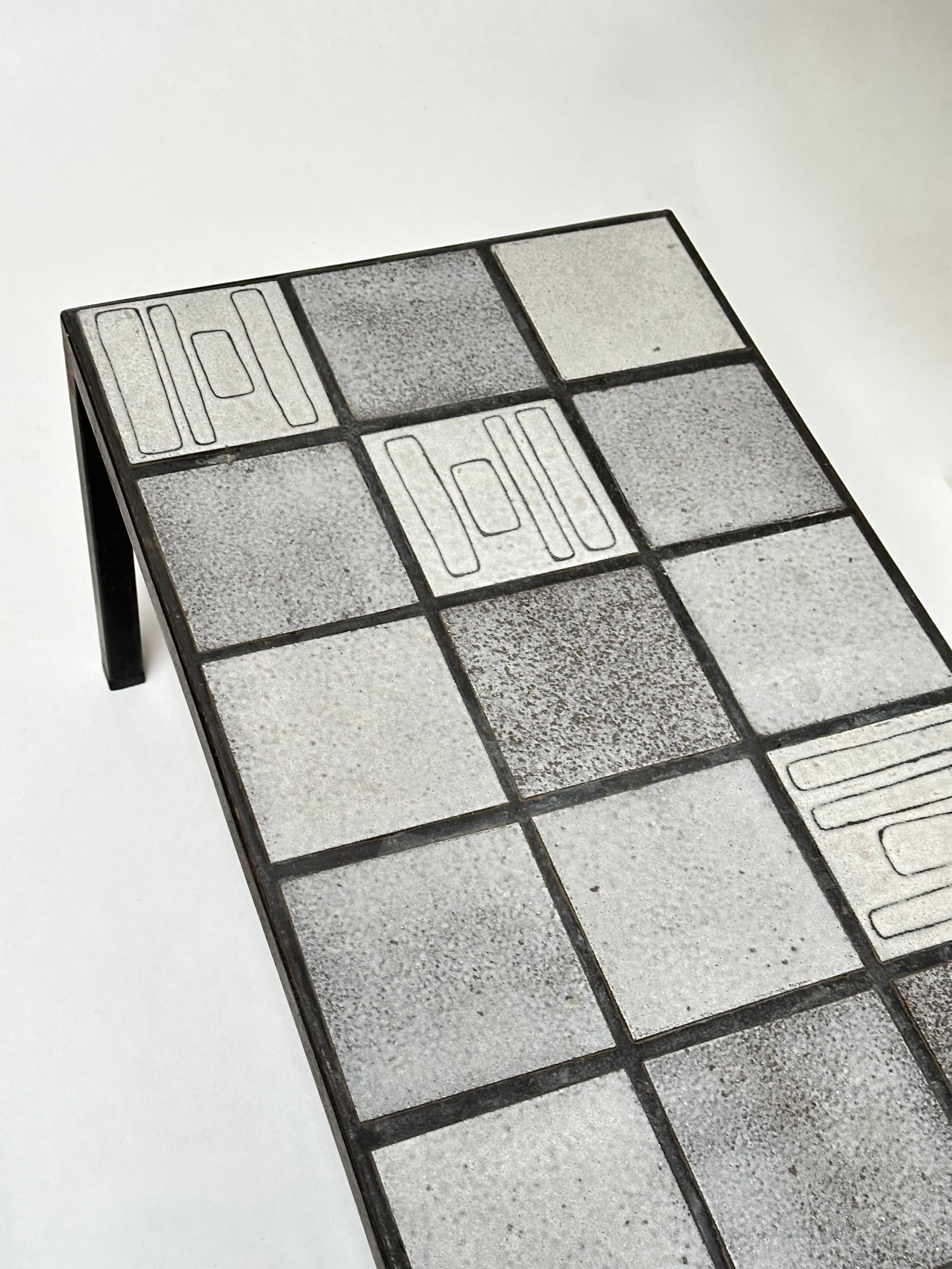 Ein außergewöhnlicher und seltener Tisch, geschaffen von Nicole Raude.

Kachelplatte aus Steinzeug in verschiedenen Grautönen, veredelt mit einem zart geometrischen Stichtiefdruckdekor und in Blei gefasst.
Schwarz lackiertes Eisengestell.

Nicole