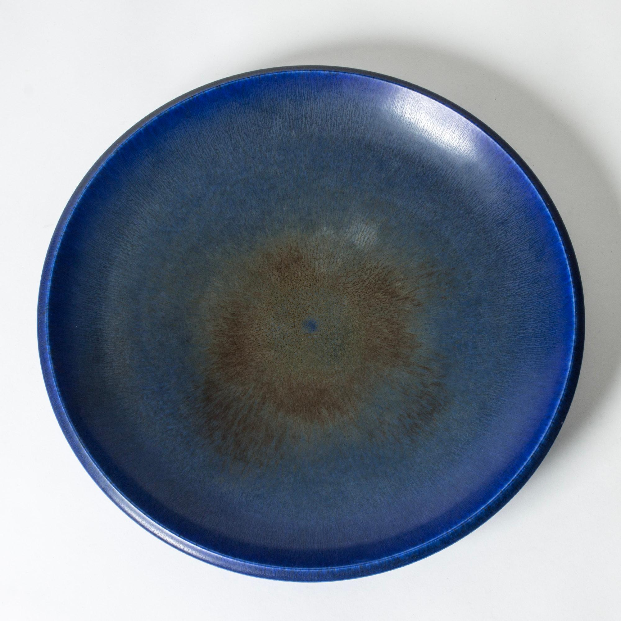 Striking, oversized stoneware platter by Berndt Friberg. Weighty. Beautiful blue hare’s fur glaze, rusty brown in the center.

Berndt Friberg was a Swedish ceramicist, renowned for his stoneware vases and vessels for Gustavsberg. His pure,