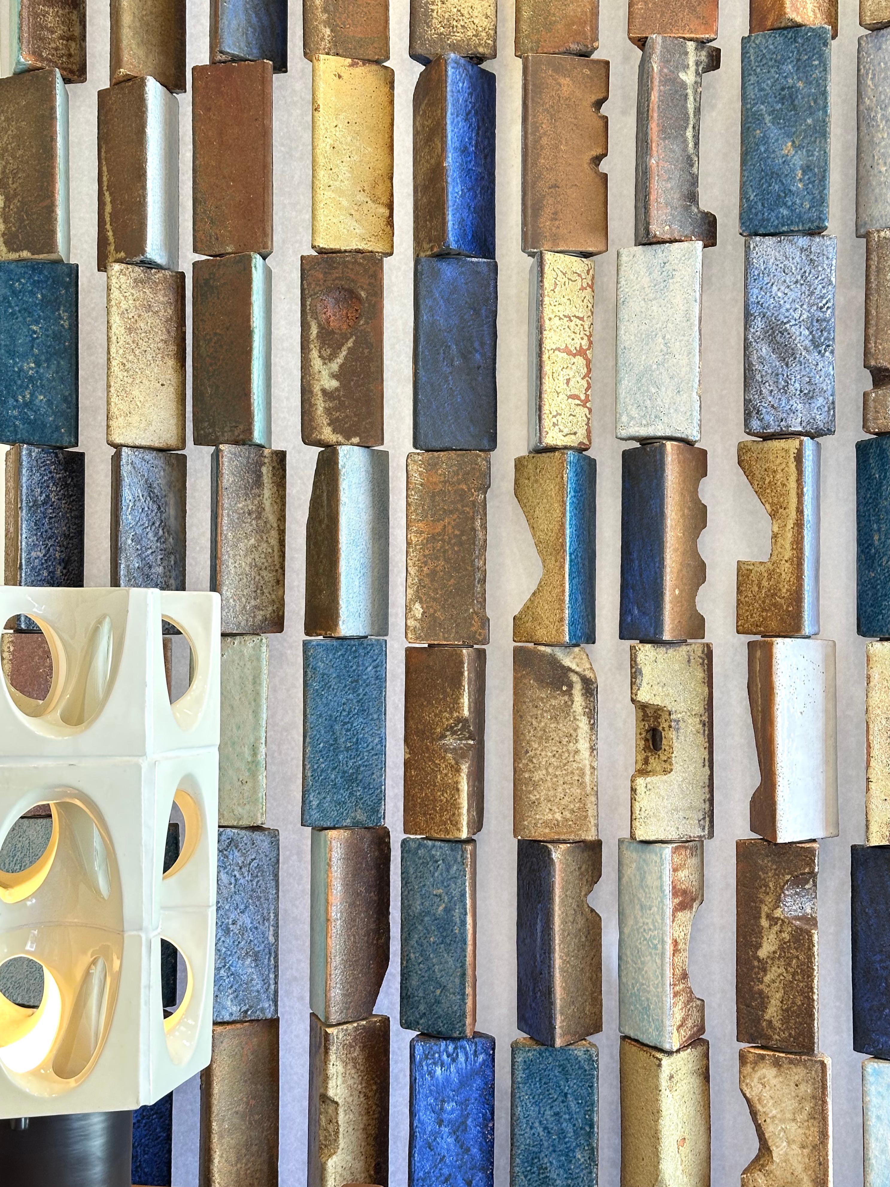 Spectacular sculpture composed of 156 three-sided modules made of grog-fired clay, designed by the artist as a room divider. 
The elements are threaded onto a metal rod and separated by washers, ensuring their mobility. 
Each prism has a triangular