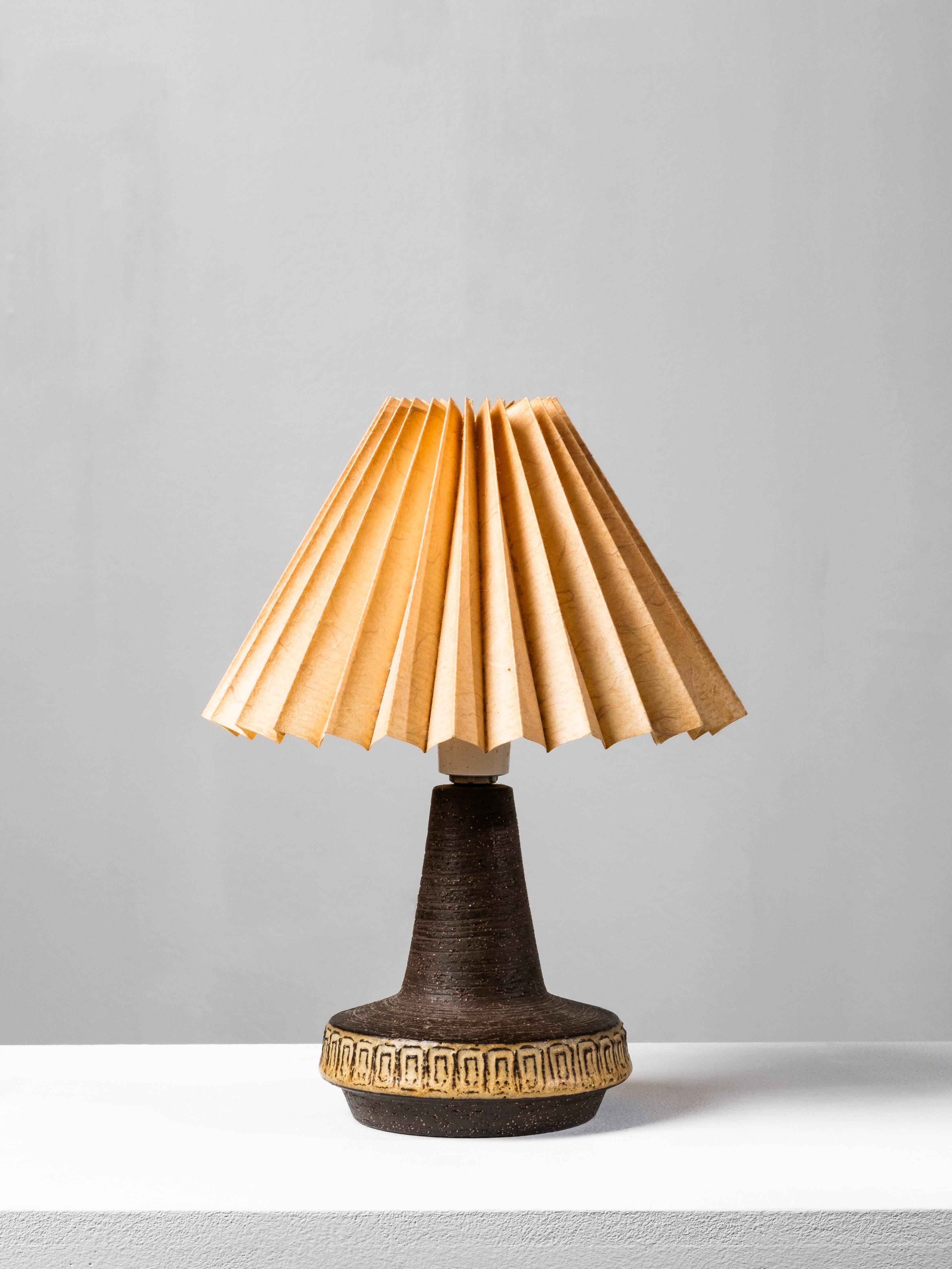Charming Danish mid-century table lamp designed and produced by Michael Andersen & Søn, Bornholm, Denmark, in the 1960s. The lamp base is crafted from textured stoneware in a deep brown glaze with a contrasting decorative band in warm ochre tones,