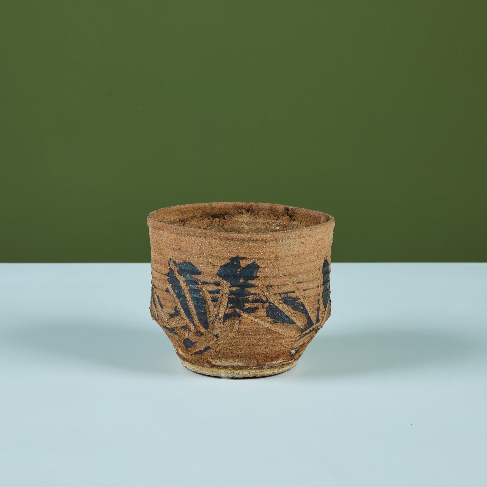 Plante de table en grès jeté à la main. La jardinière présente un extérieur nervuré avec des détails incisés et une glaçure noire peinte sur le récipient non émaillé. 
Signé 