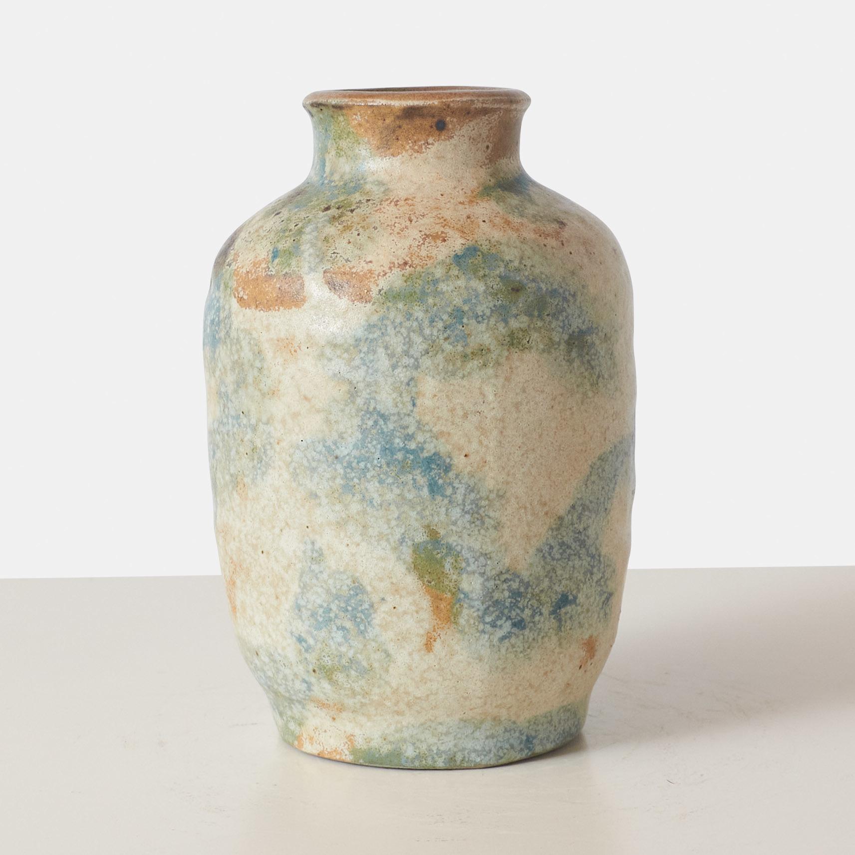 A stoneware vase created by Danish ceramic artist Bode Willumsen features a unique frosting technique that creates a textured, frosted appearance in white, blue, and green hues. Willumsen, who had his own workshop, is known for his intricate designs