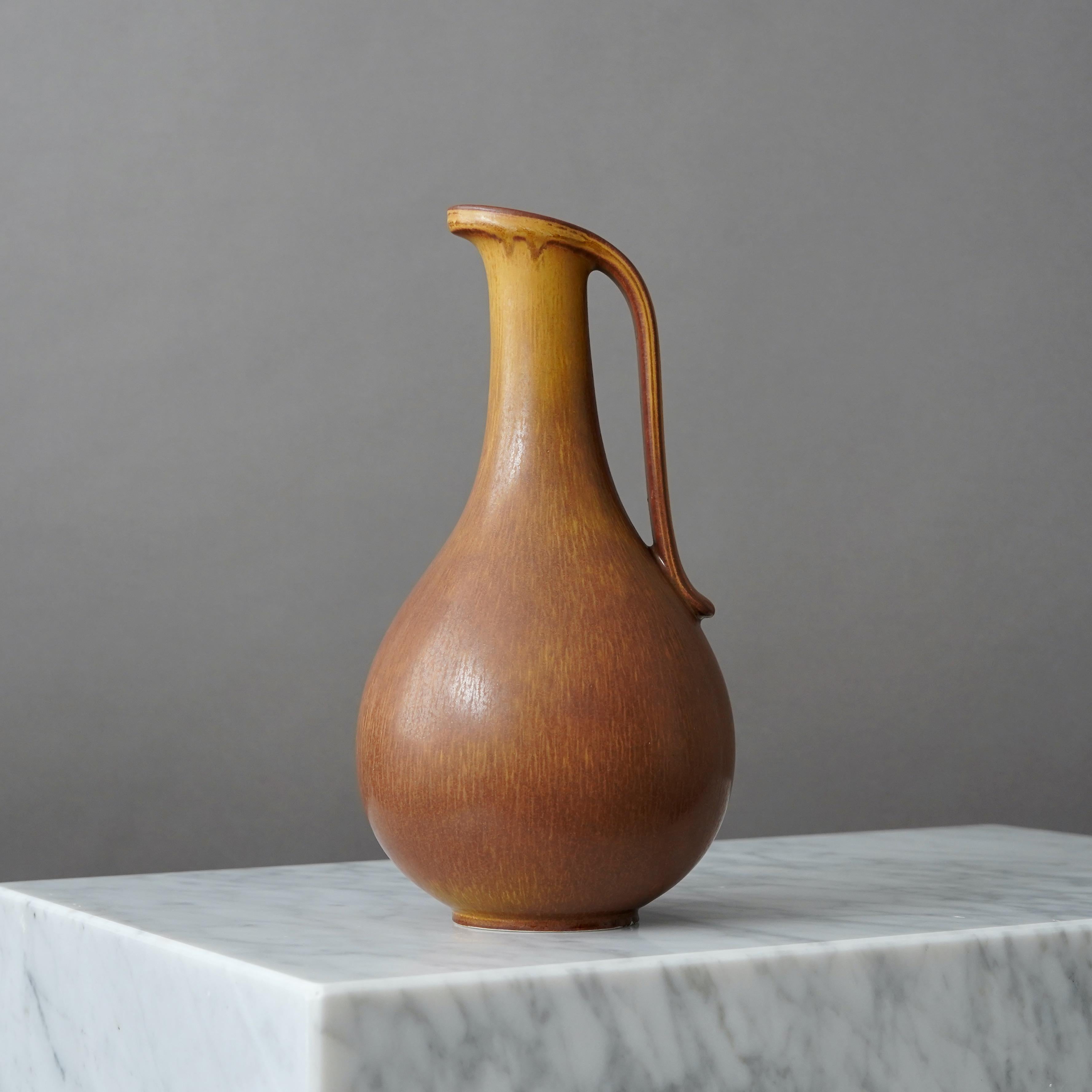 Un bellissimo vaso in gres con manico e smalto sorprendente.
Disegnata da Gunnar Nylund per Rorstrand, Svezia, anni '1950.  

Buone condizioni. Marcato come secondo di fabbrica a causa di una piccola scheggiatura dovuta alla produzione sul bordo del