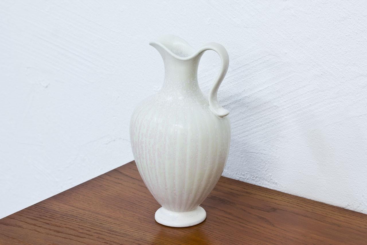 Stoneware jug/ vase designed by Gunnar Nylund for Rörstrand in Sweden during the 1940s. Textured glaze in speckled white with slight pink on one side. Hand signed. Second line of production.