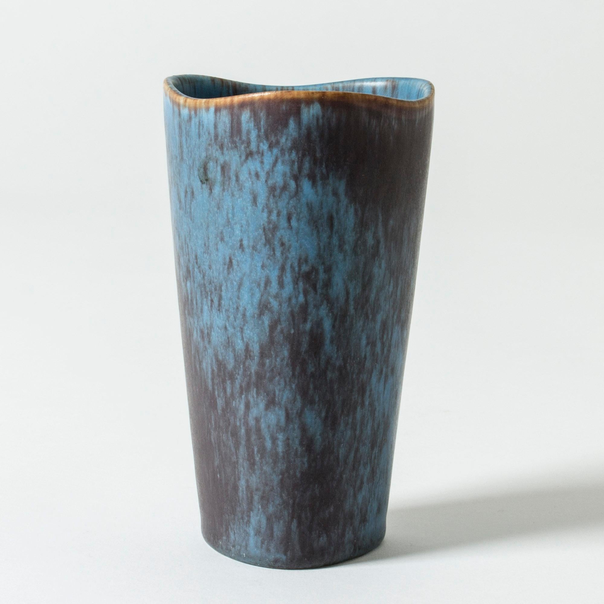 Vase aus Steingut von Gunnar Nylund in klarer Form. Der gewellte Rand lockert die Form auf. Leuchtend blaue Glasur mit violetten Streifen.

Gunnar Nylund war einer der einflussreichsten Keramiker und Designer der schwedischen Mitte des