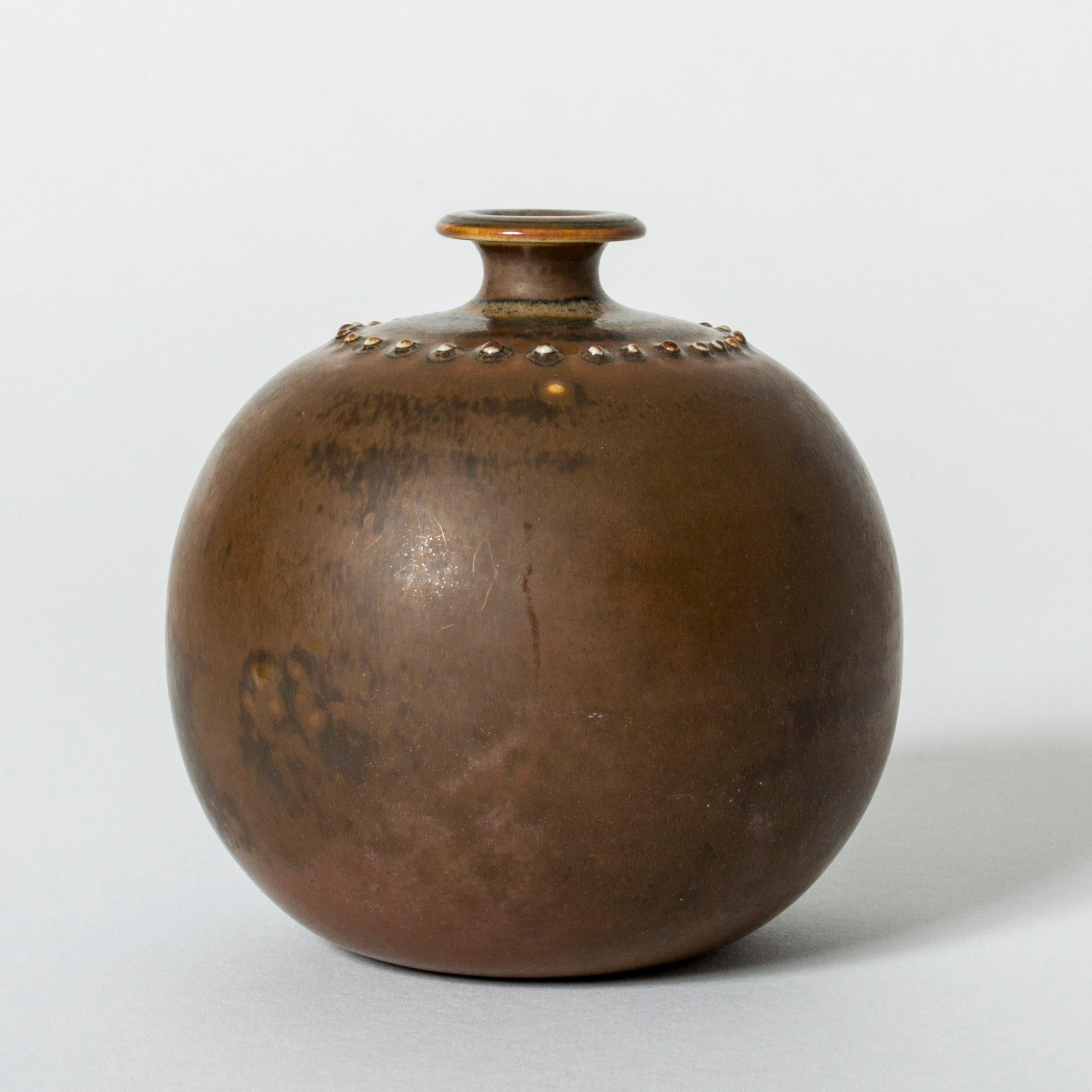 Cute stoneware vase by Stig Lindberg, in a plump design. Decor of spheres around the mouth. Brown glaze in lighter and darker hues.