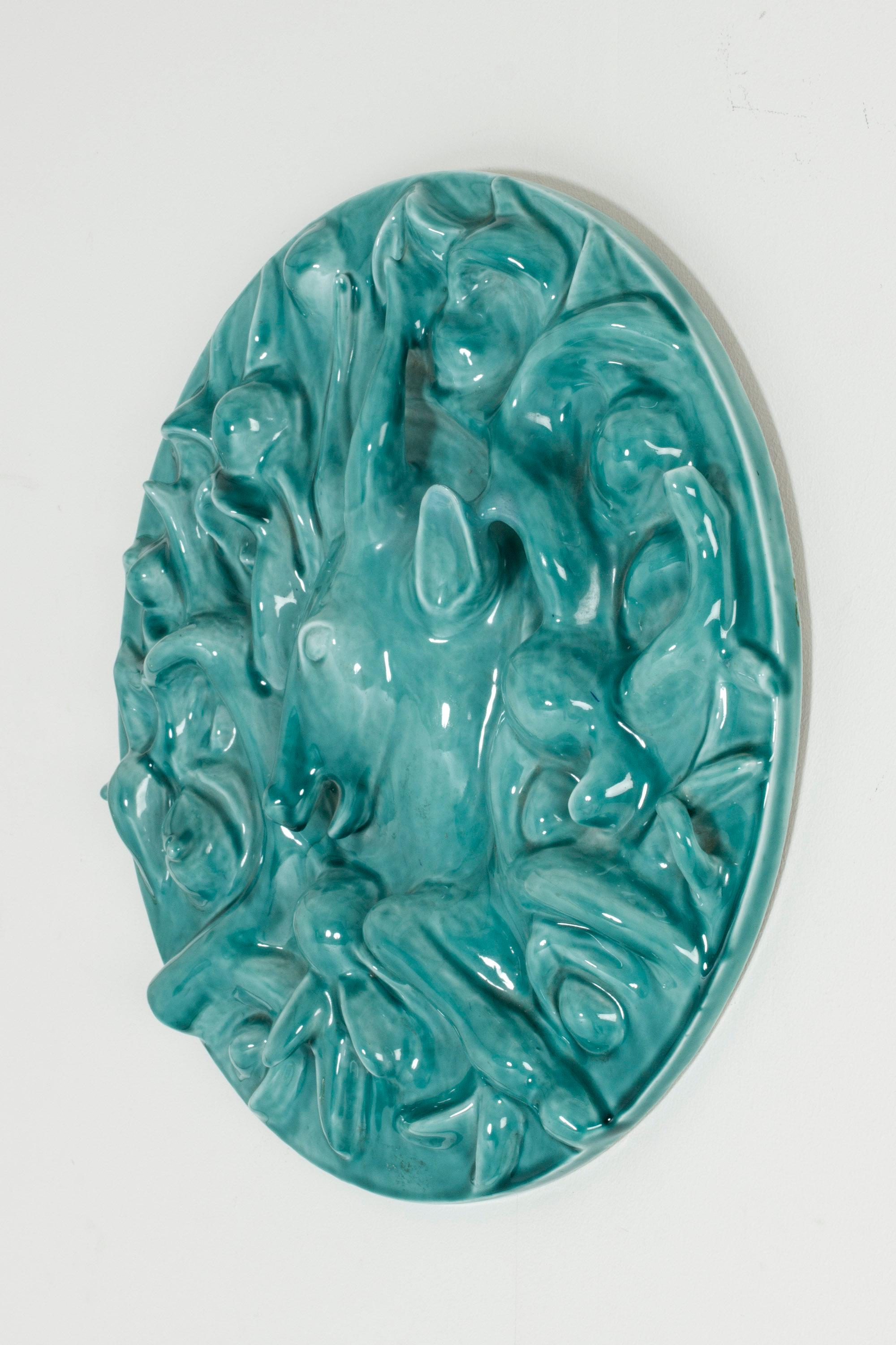 Striking stoneware wall relief by Axel Salto. Large round shape with motif of a deer in foliage, preparing to take a bite of an apple. Beautiful aquamarine glaze.