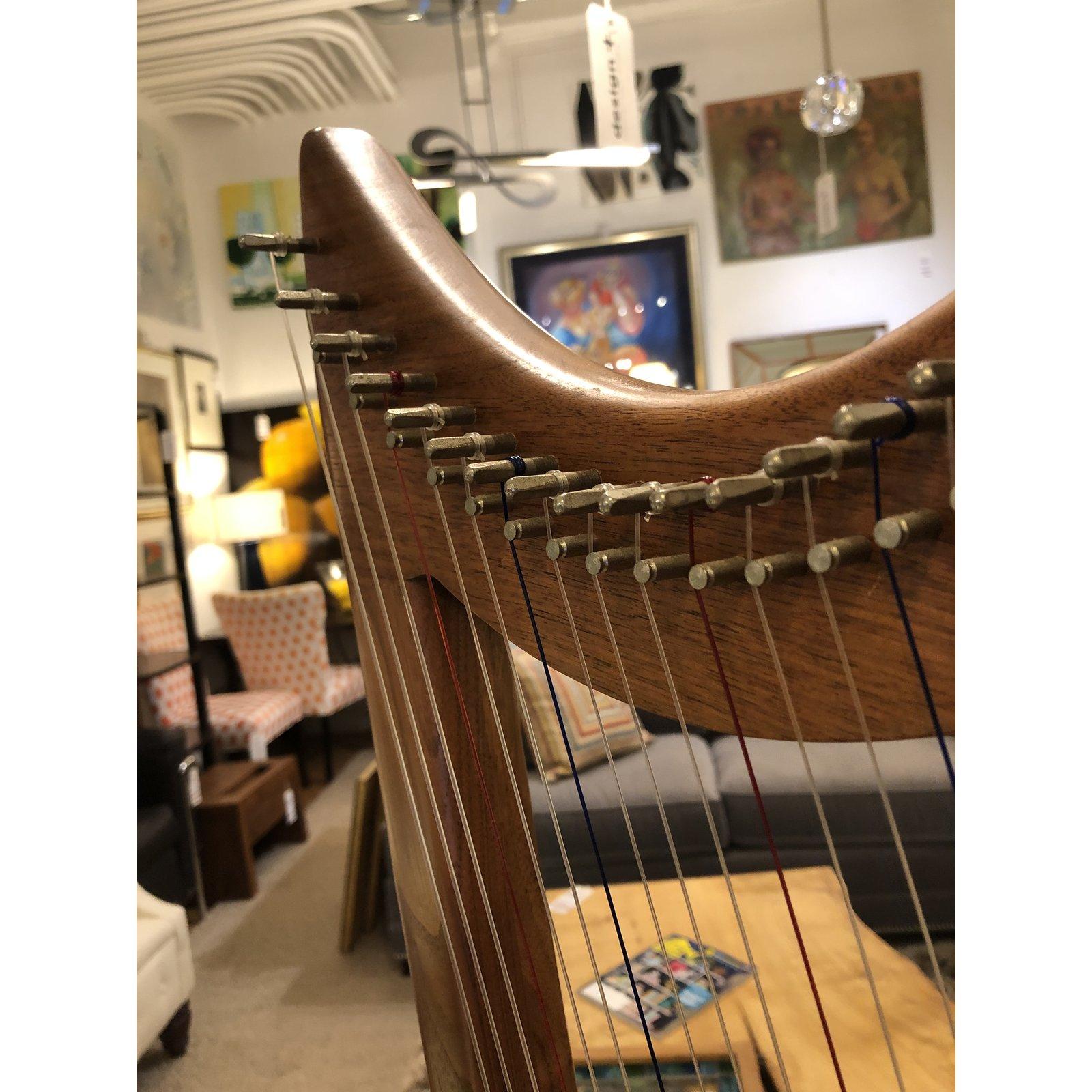An Eve 22 Lamp Harp by Stoney End. A Gothic-style lap harp with 22 strings, offering three octaves from G to G. Light-weight and compact, this harp is perfect for travel and has rich tone and surprising volume for its size. The wood is a