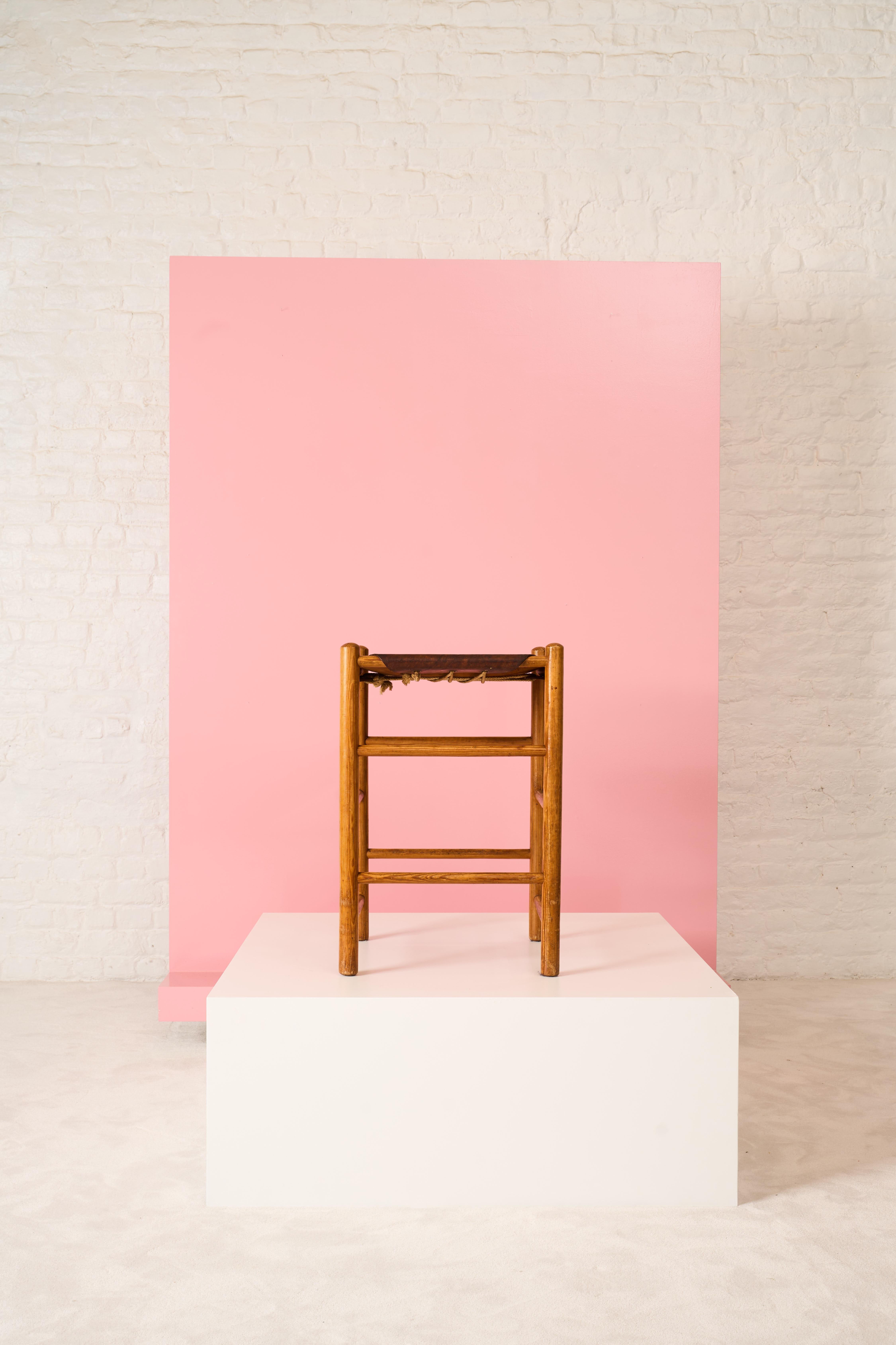 Tabouret vintage conçu par Ate van Apeldoorn pour Houtwerk Hattem dans les années 1970. Le tabouret est fabriqué en bois de pin massif et possède un siège en cuir noué à la base. Le cuir présente une belle patine.