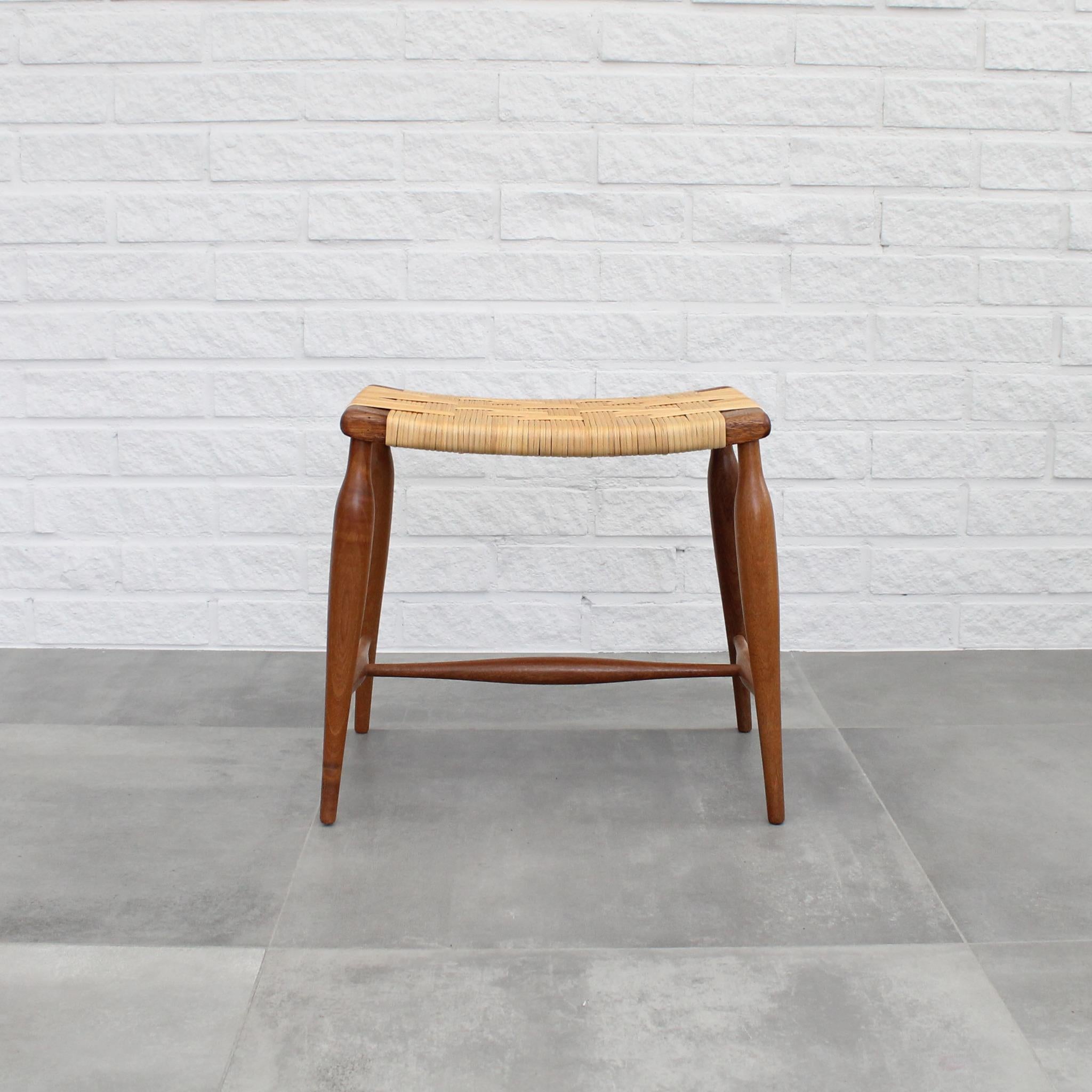 Early version of Stool 967, originally designed by Josef Frank in 1938 for Firma Svenskt Tenn. Crafted from solid mahogany with a rattan seat, this model bears a striking resemblance to the standard 967, differing primarily in the shape of the seat